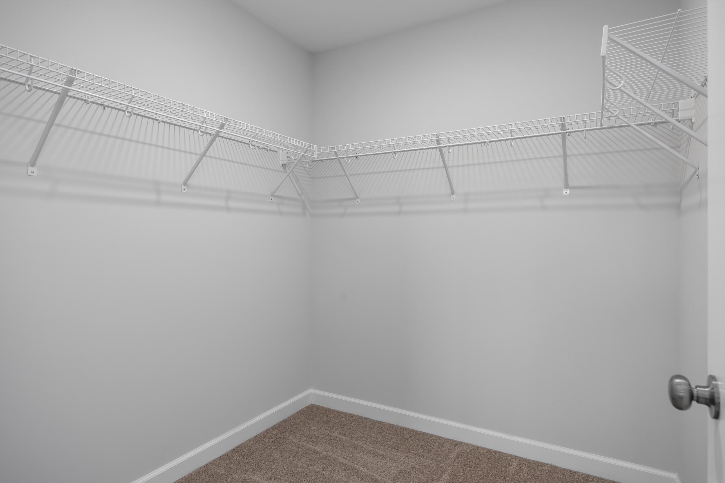 Walk-in closet with white wire shelving in the master suite of The Warren home design by Davidson Homes.
