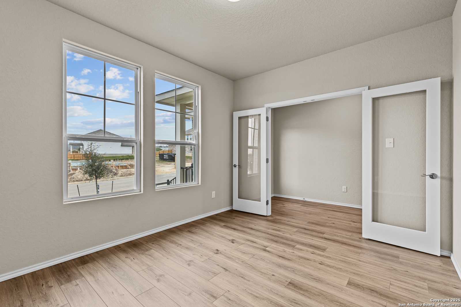 Sunlit flex room with large windows overlooking yard, open French doors, and hardwood floors in Davidson Homes The Douglas F, San Antonio