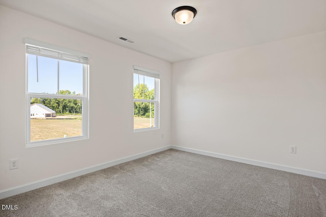 Bright carpeted bedroom with dual windows overlooking scenic views in Davidson Homes The Hickory II B, Lillington, North Carolina