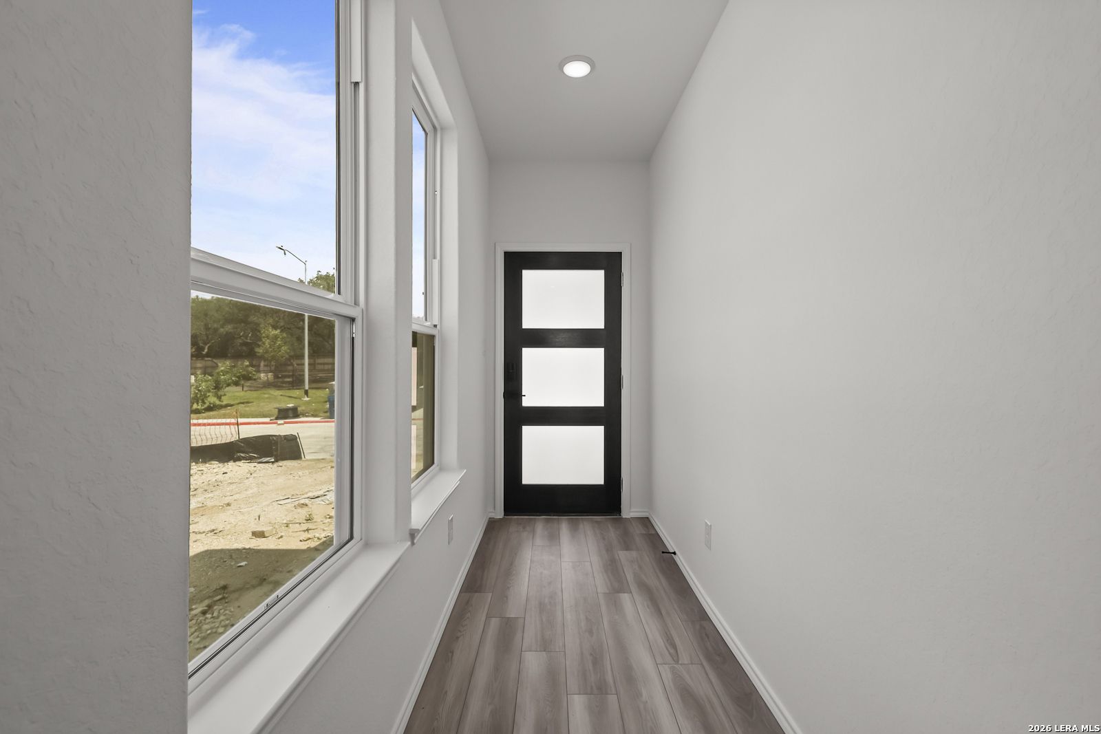 Bright entryway with modern black door and wood-look flooring in The Florence B floor plan at Meadows at Oak Creek, TX.