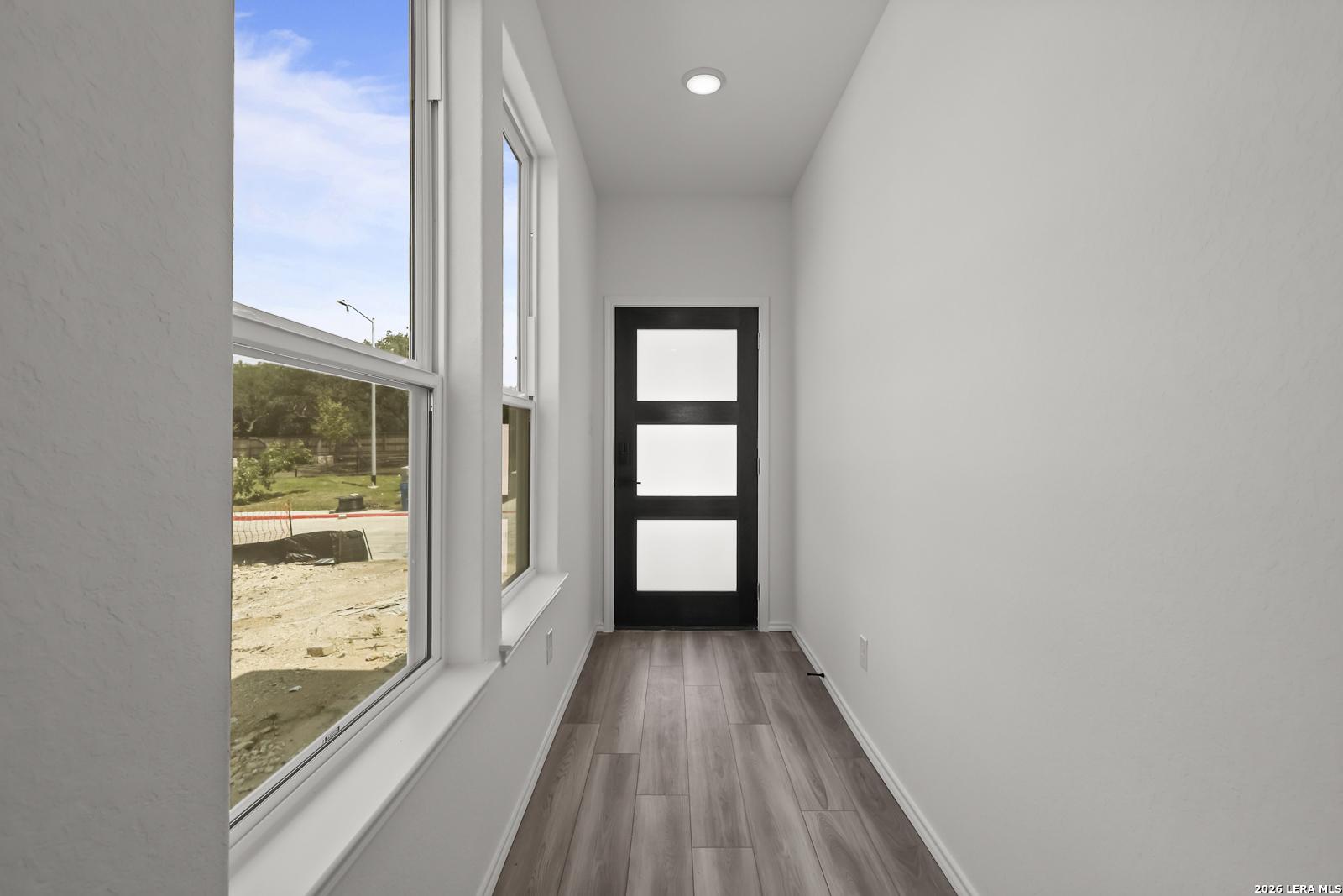 Bright entryway with modern black door and wood-look flooring in The Florence B floor plan at Meadows at Oak Creek, TX.