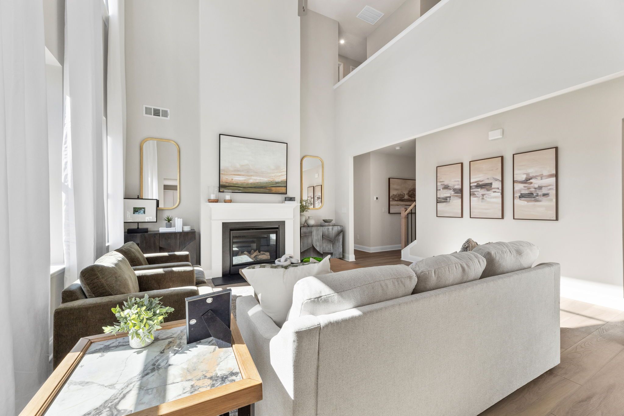 Spacious living room at Melody Lakeside Estates in Buford GA featuring gas fireplace, modern sofas, hardwood floors, and high ceilings