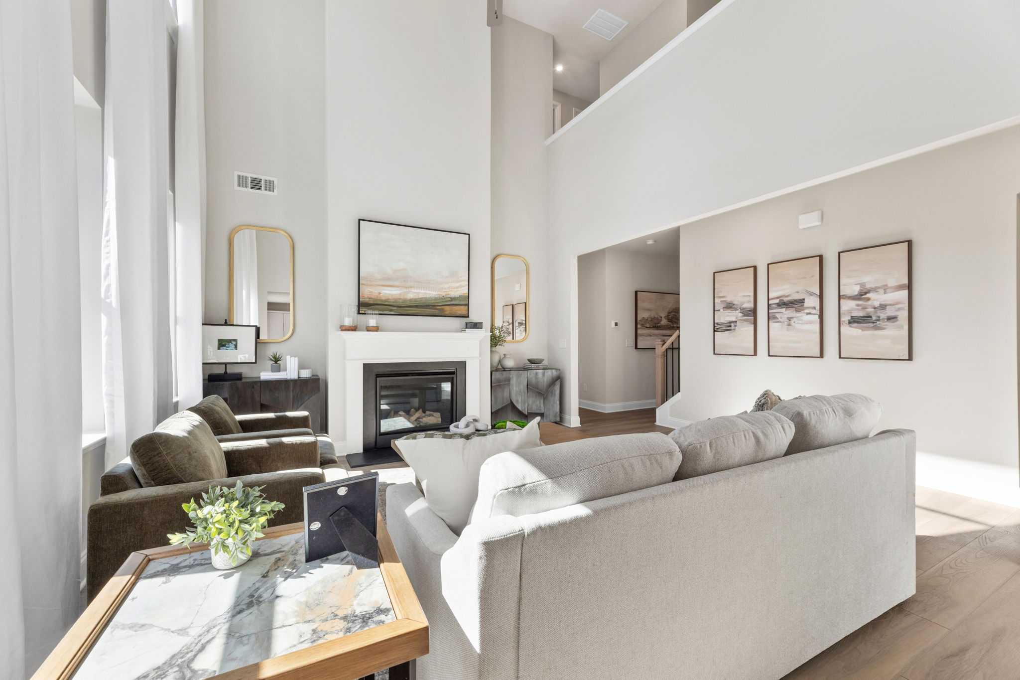 Spacious living room at Melody Lakeside Estates in Buford GA featuring gas fireplace, modern sofas, hardwood floors, and high ceilings