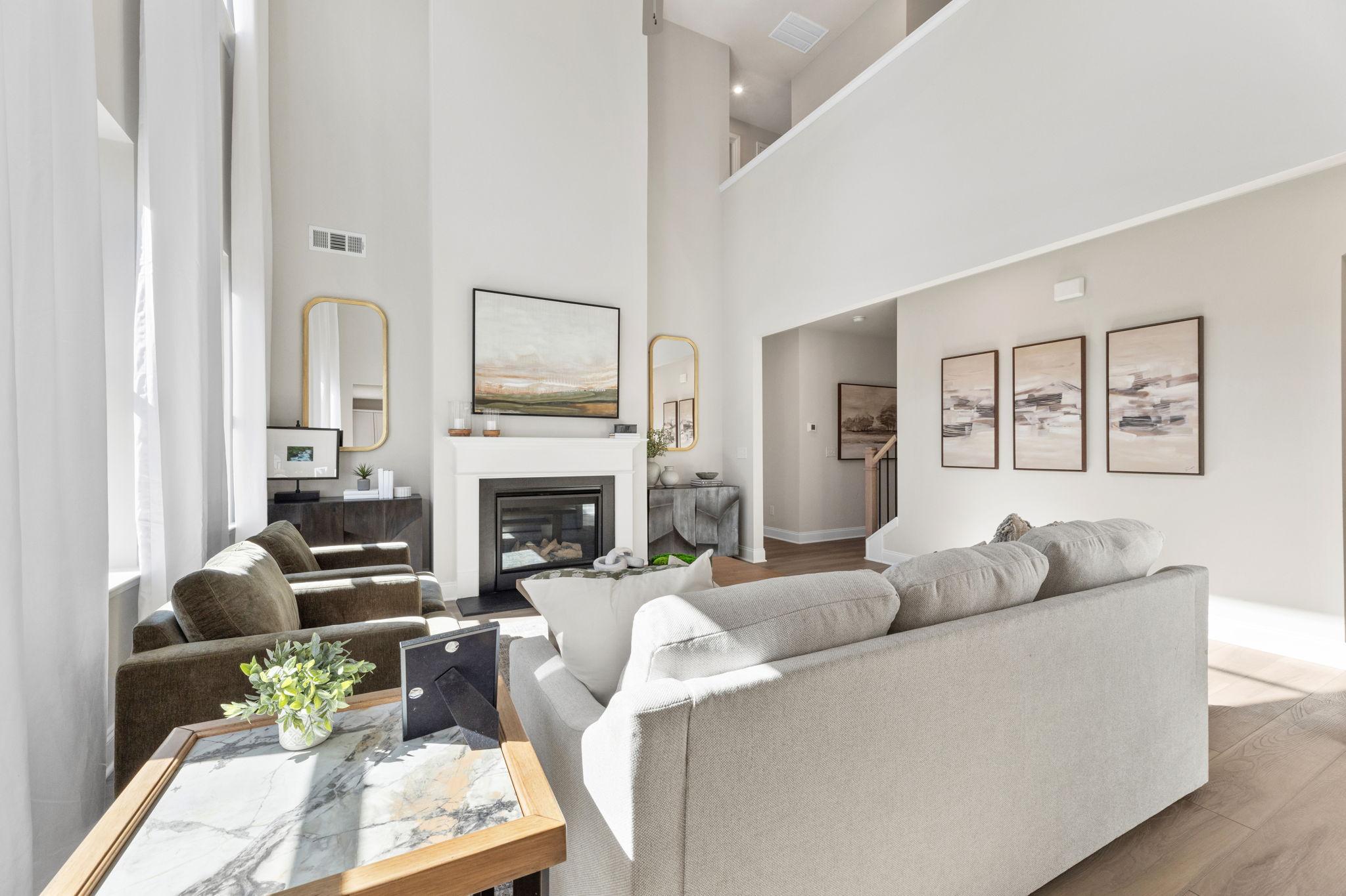 Spacious living room at Melody Lakeside Estates in Buford GA featuring gas fireplace, modern sofas, hardwood floors, and high ceilings