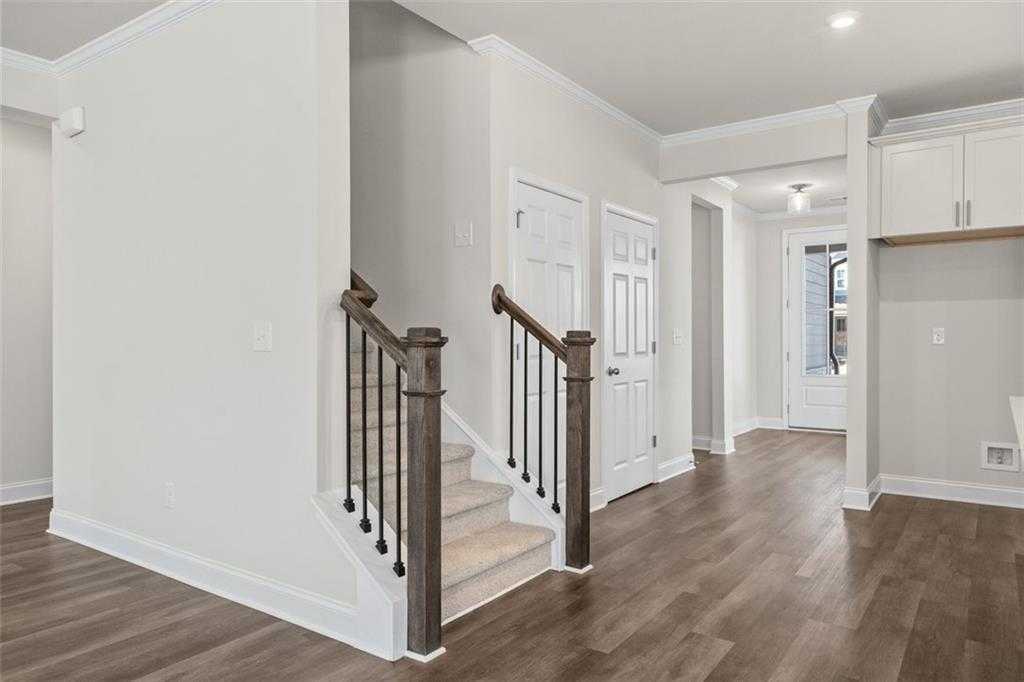 Elegant wooden staircase with iron balusters in bright hallway of Davidson Homes The Ash C at Wehunt Meadows, Hoschton