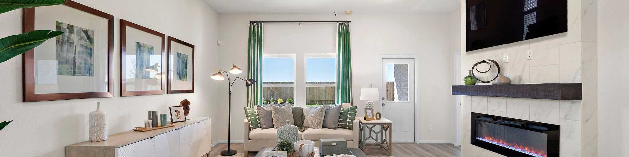 Spacious modern living room with gas fireplace, beige sofa, armchairs, and TV in Celina new home