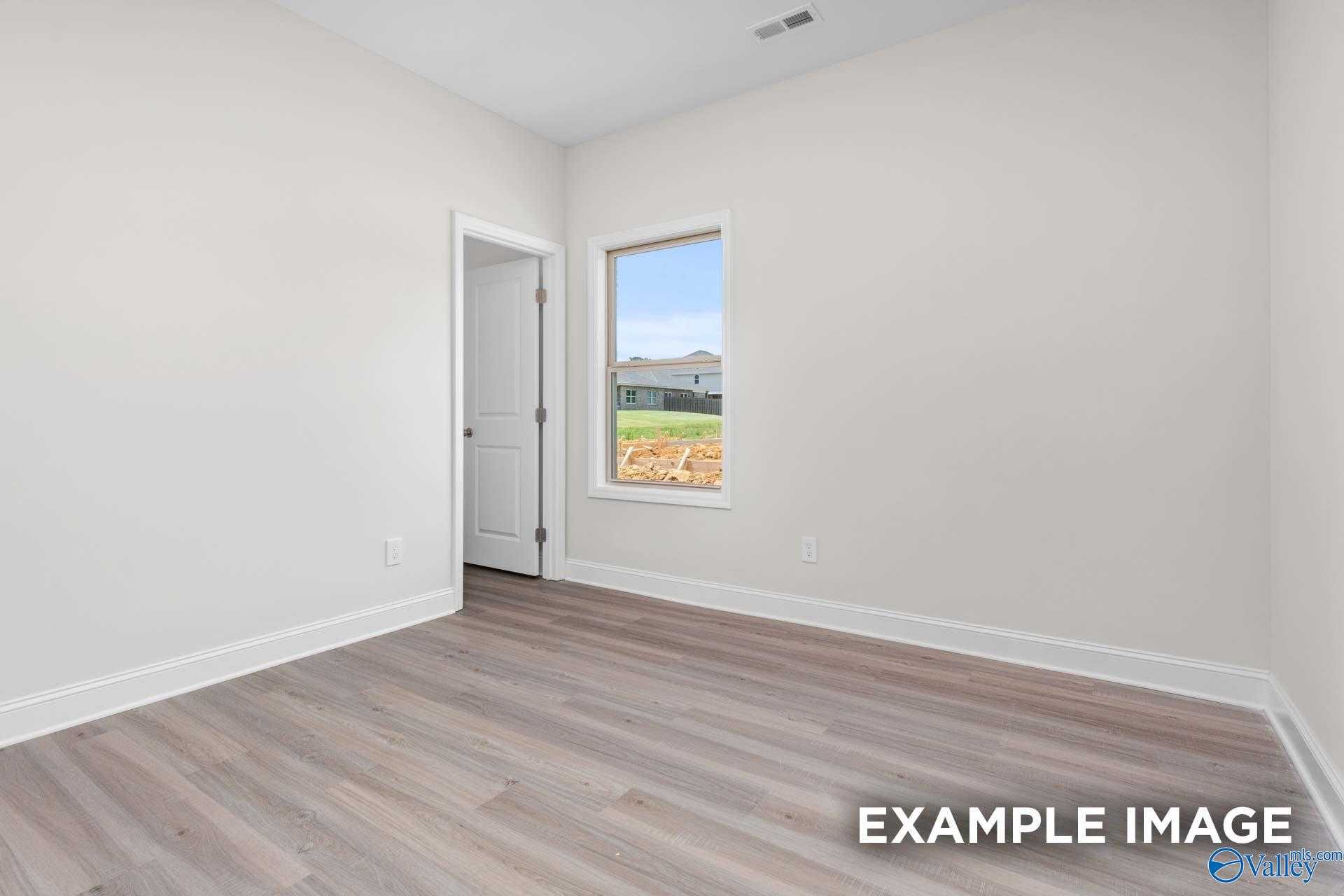 Bright empty bedroom with large window and green field view in The Daphne D 4-bedroom home, The Highlands, Arab, Alabama