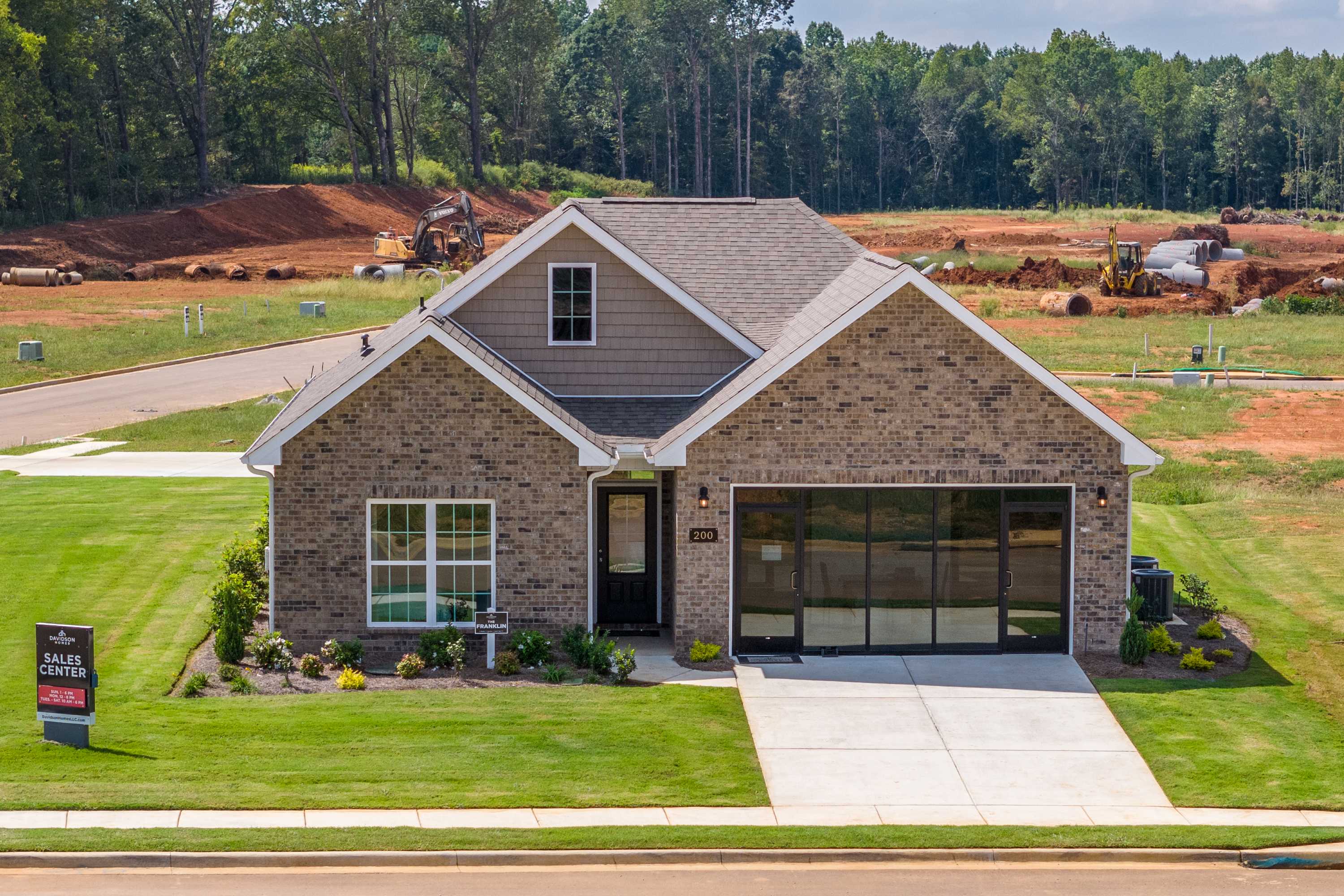 New brick ranch home exterior at Wood Trail in Toney, Alabama by Davidson Homes with garage, porch, and landscaped yard