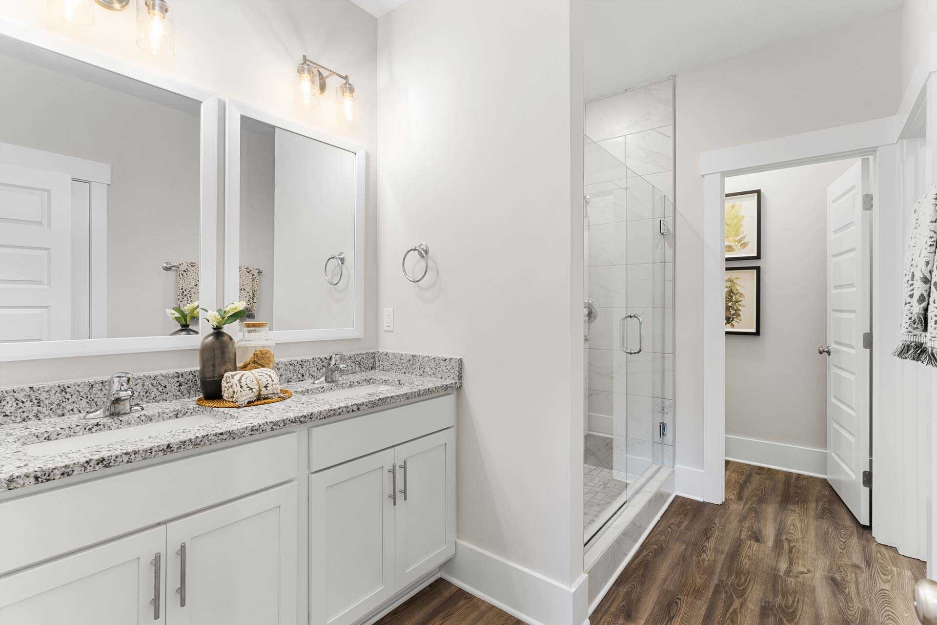 Spacious primary bathroom at The Meadows in Athens Alabama featuring double vanity quartz counters glass shower and wood floors