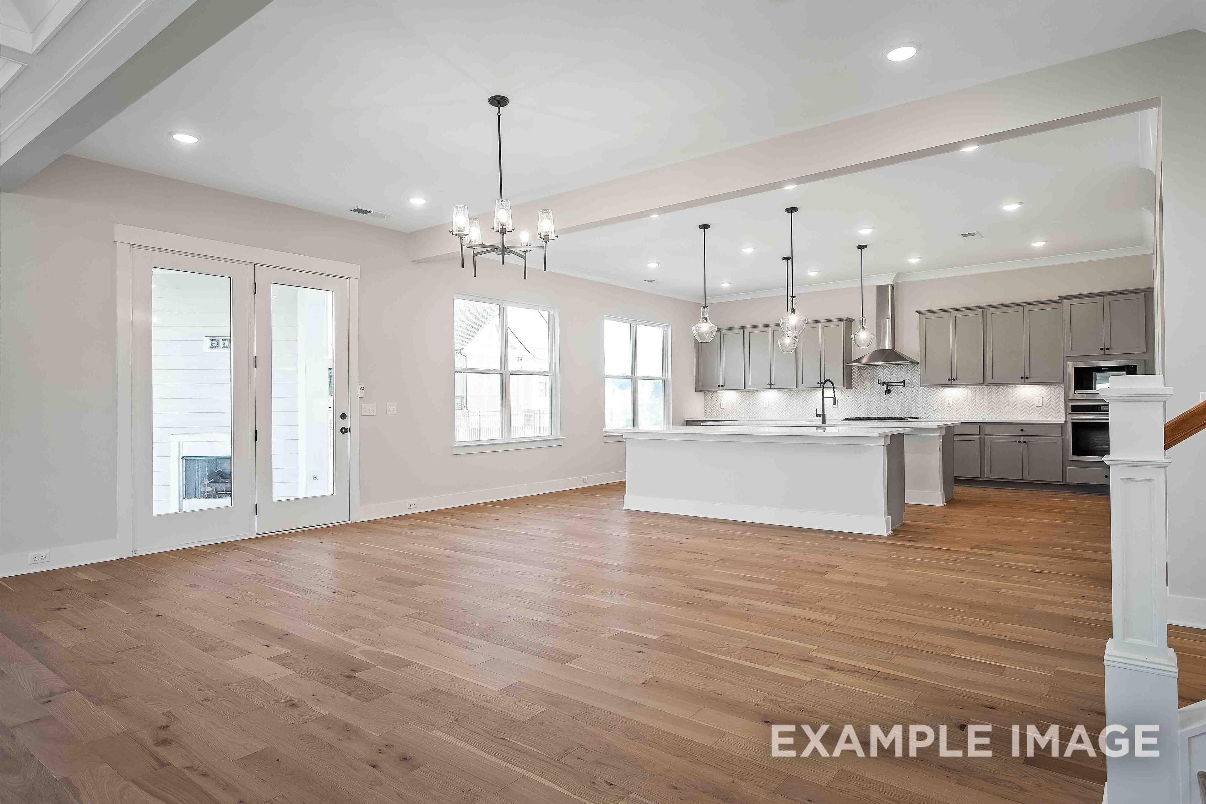 Spacious open-concept kitchen in Alston A home with gray shaker cabinets, white island, hardwood floors, and large windows