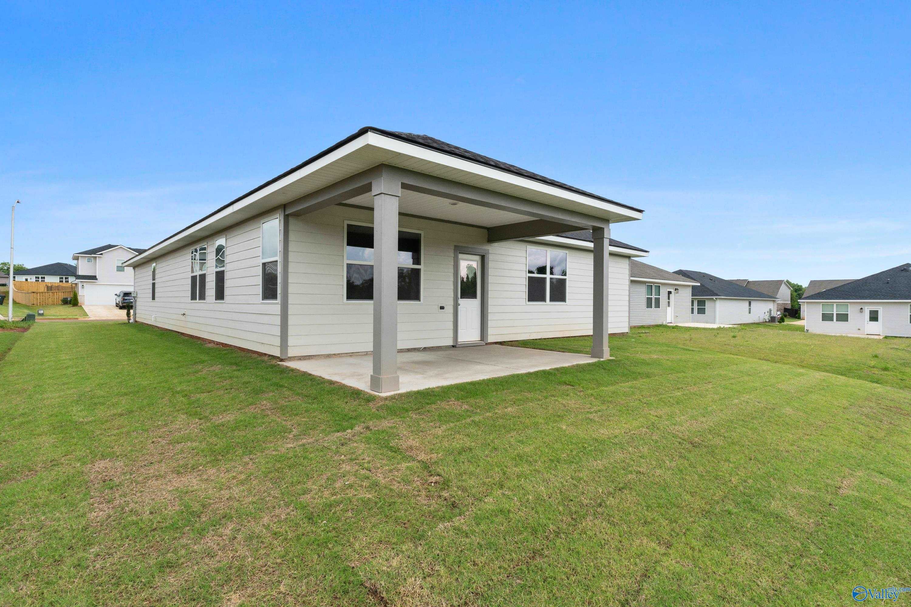Modern single-story 4-bedroom home exterior with covered porch, white siding, and green lawn in Carroll Green, Harvest, Alabama