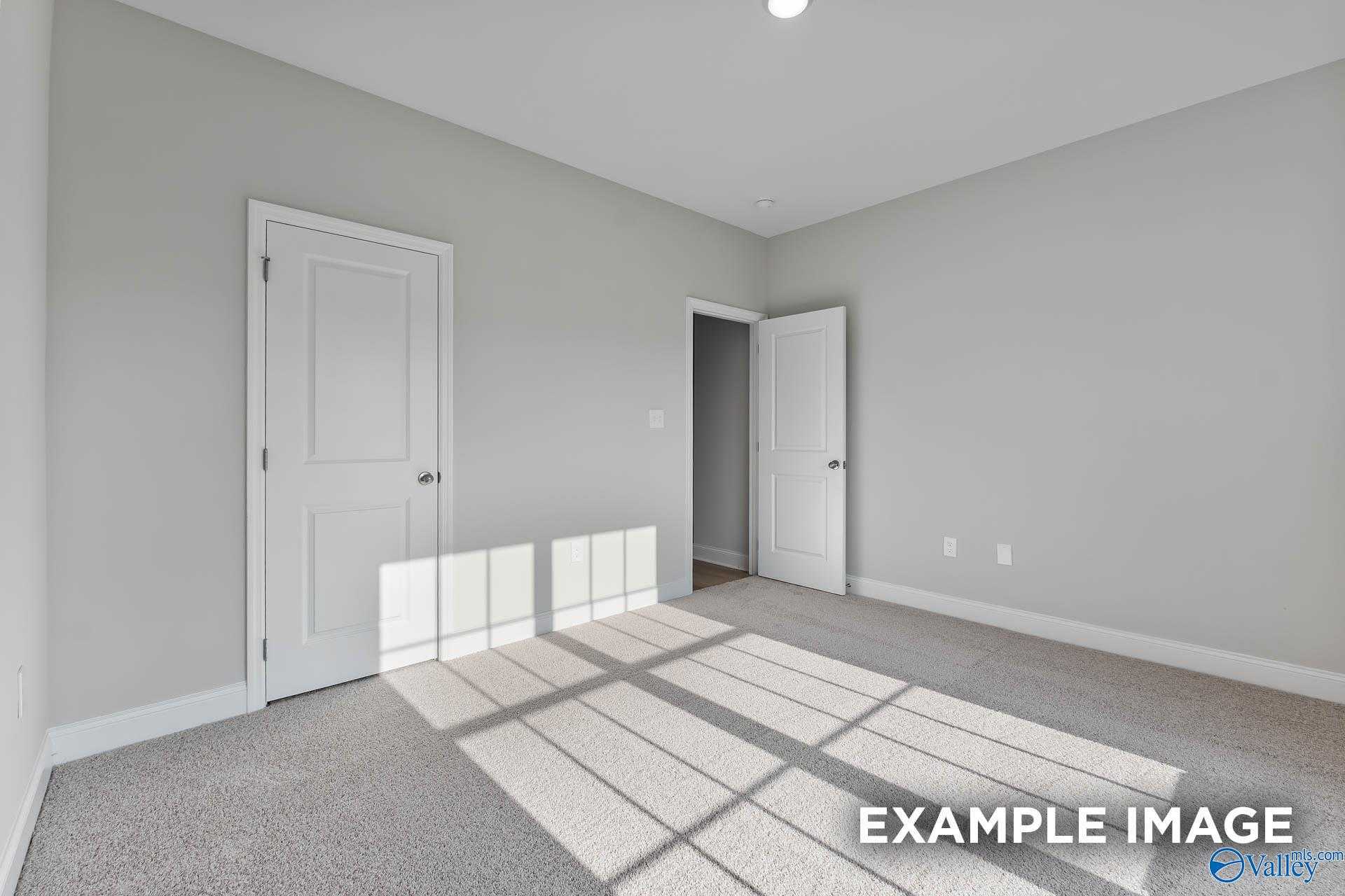 Bright bedroom with light gray walls, white doors, carpeted floor, and natural sunlight in Davidson Homes The Daphne C, New Market, Alabama
