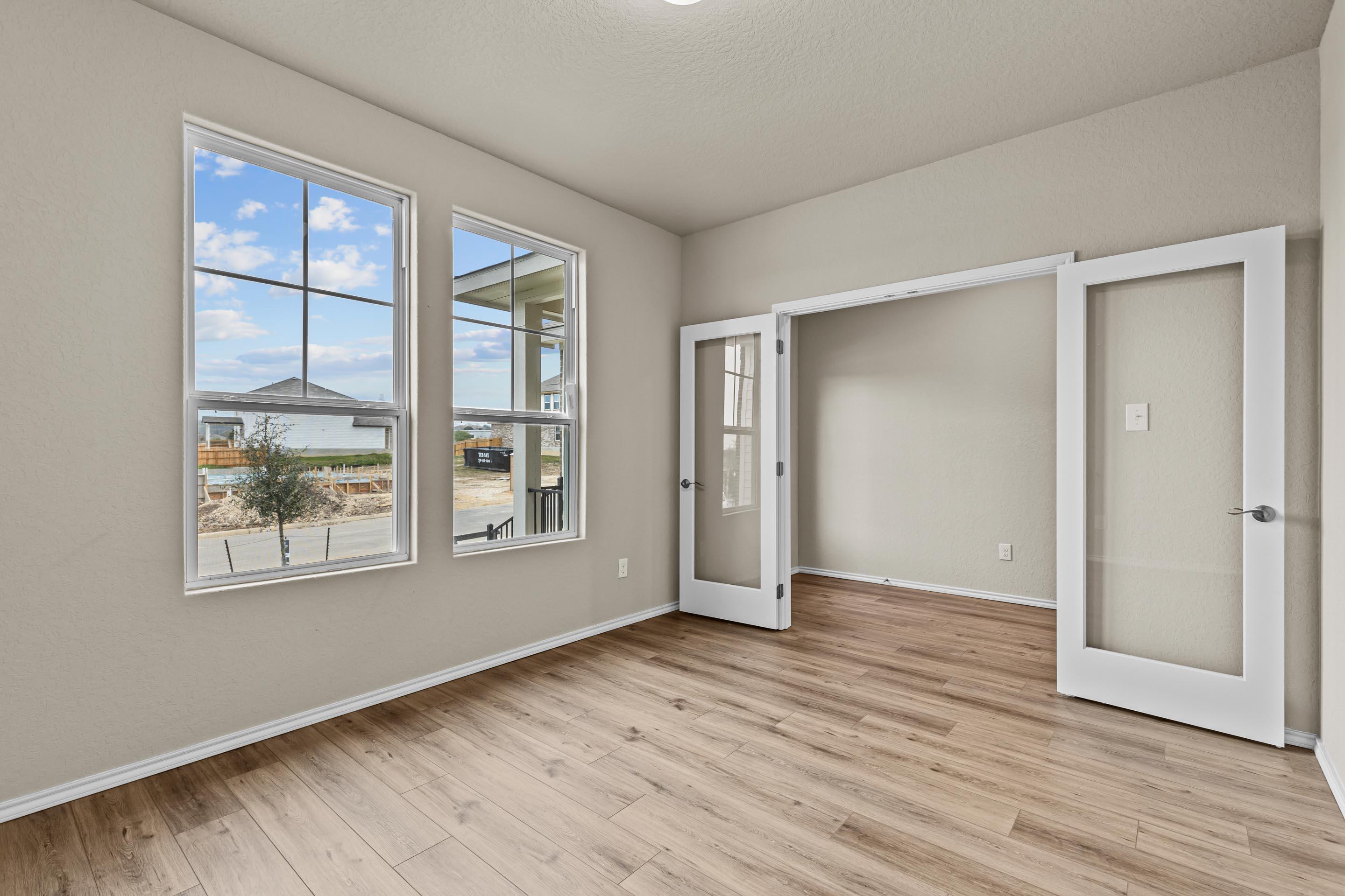 Bright study room with large windows, French doors, and hardwood floors in Davidson Homes The Douglas F, San Antonio