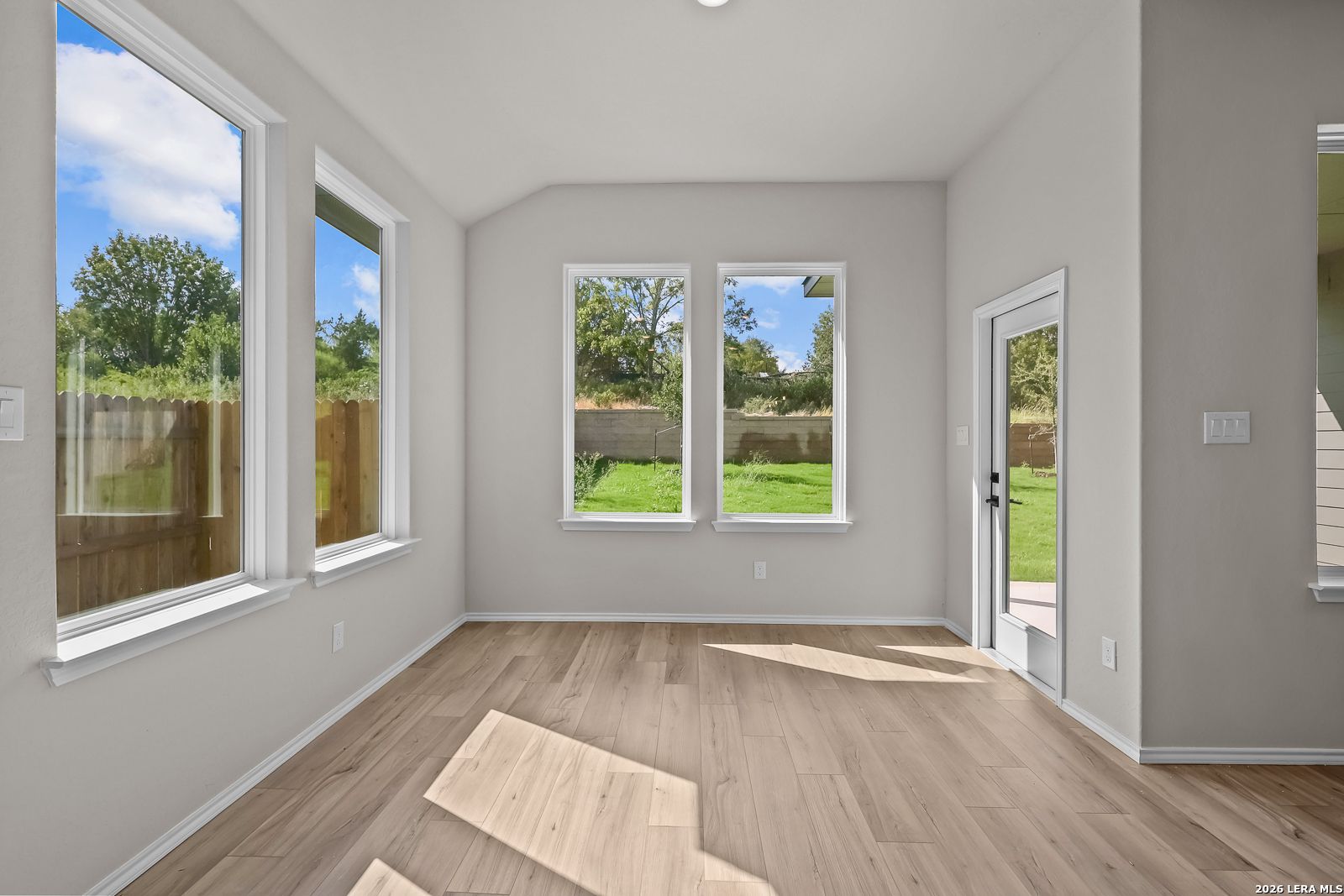 Bright sunlit living room with wood-look flooring and backyard views in Davidson Homes The Sequoia C, Royal Crest, San Antonio