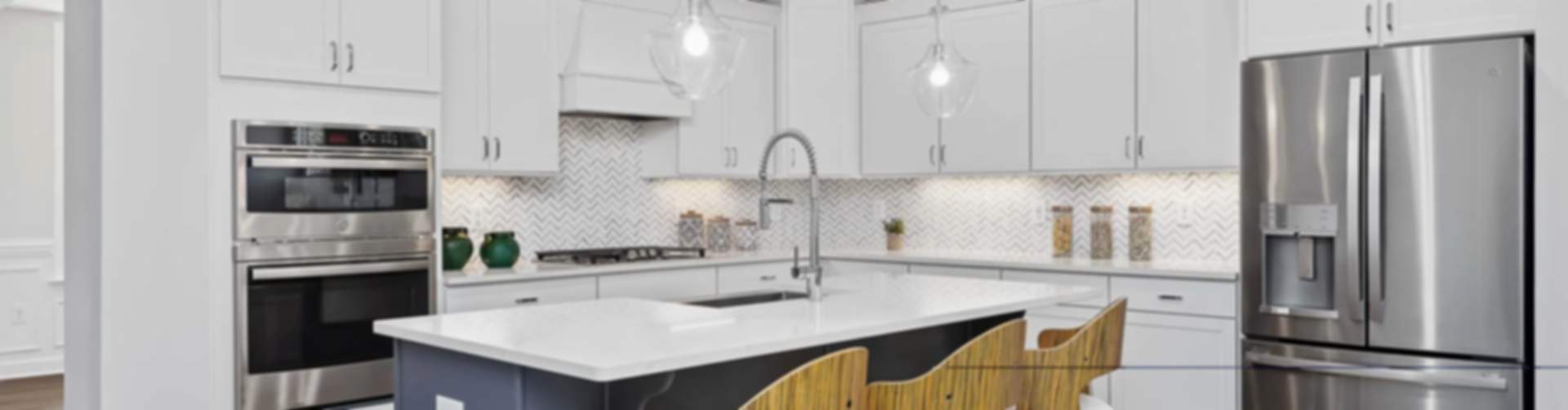 Spacious modern kitchen in new Wendell home with white cabinets, blue island, stainless steel appliances