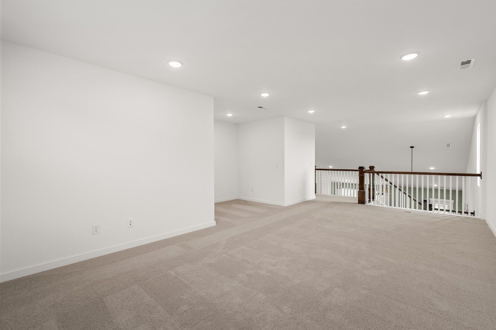 Spacious upstairs loft with beige carpet, white walls, recessed lights, and wooden railing overlook in Davidson Homes The Ridgeport, Gallatin, TN