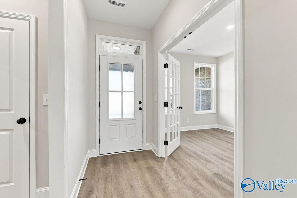 Bright foyer with glass-paneled front door and luxury vinyl plank flooring in Davidson Homes The Rockford, Hartselle, Alabama