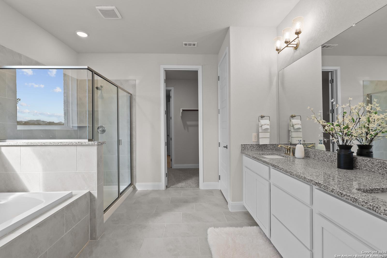 Modern master bathroom featuring frameless glass shower, soaking tub, and double granite vanity in Davidson Homes The Lanier H, Ladera, San Antonio