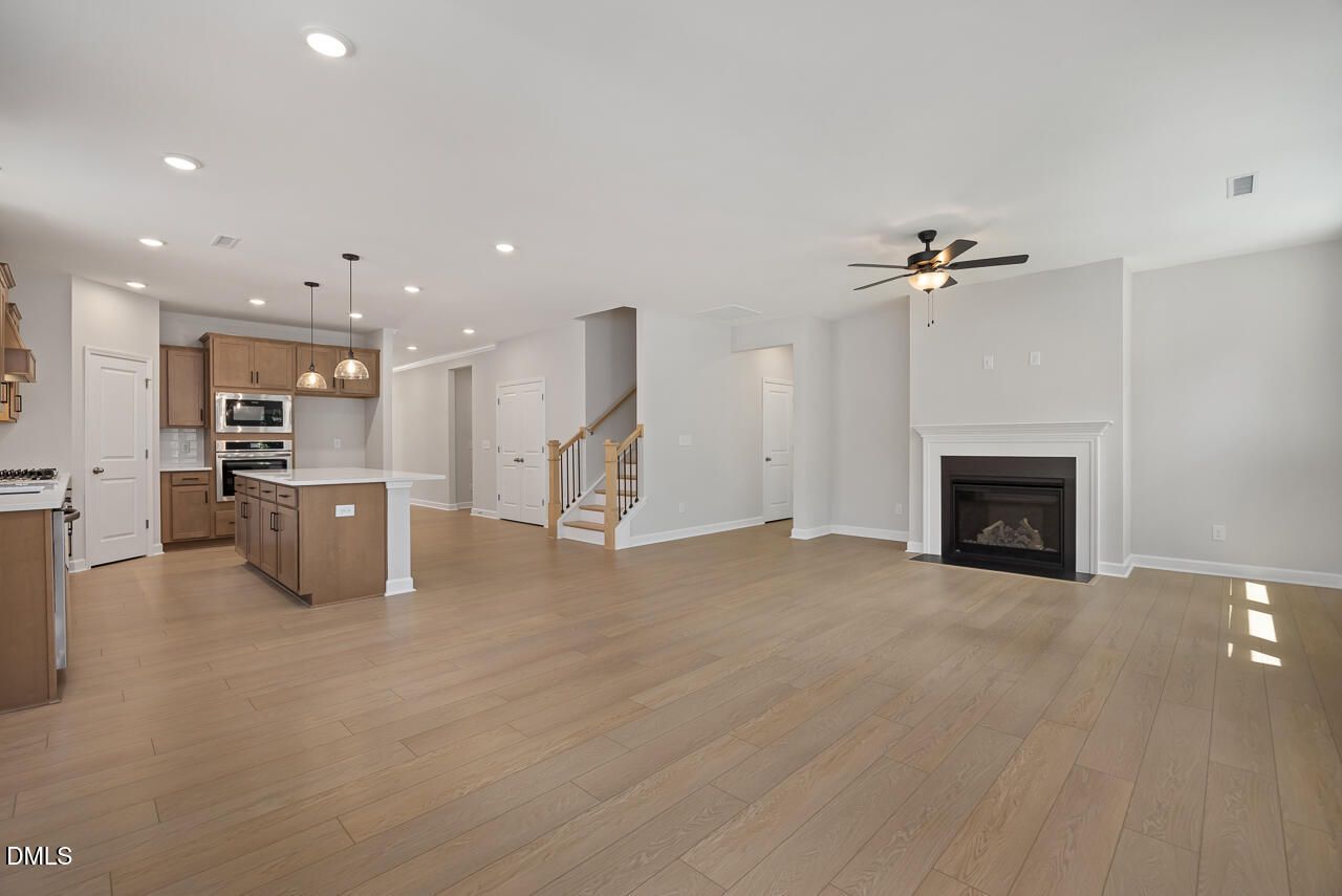 Open-concept living room and kitchen with fireplace in Ashport L floor plan at Sage on North Main, Wake Forest, NC.