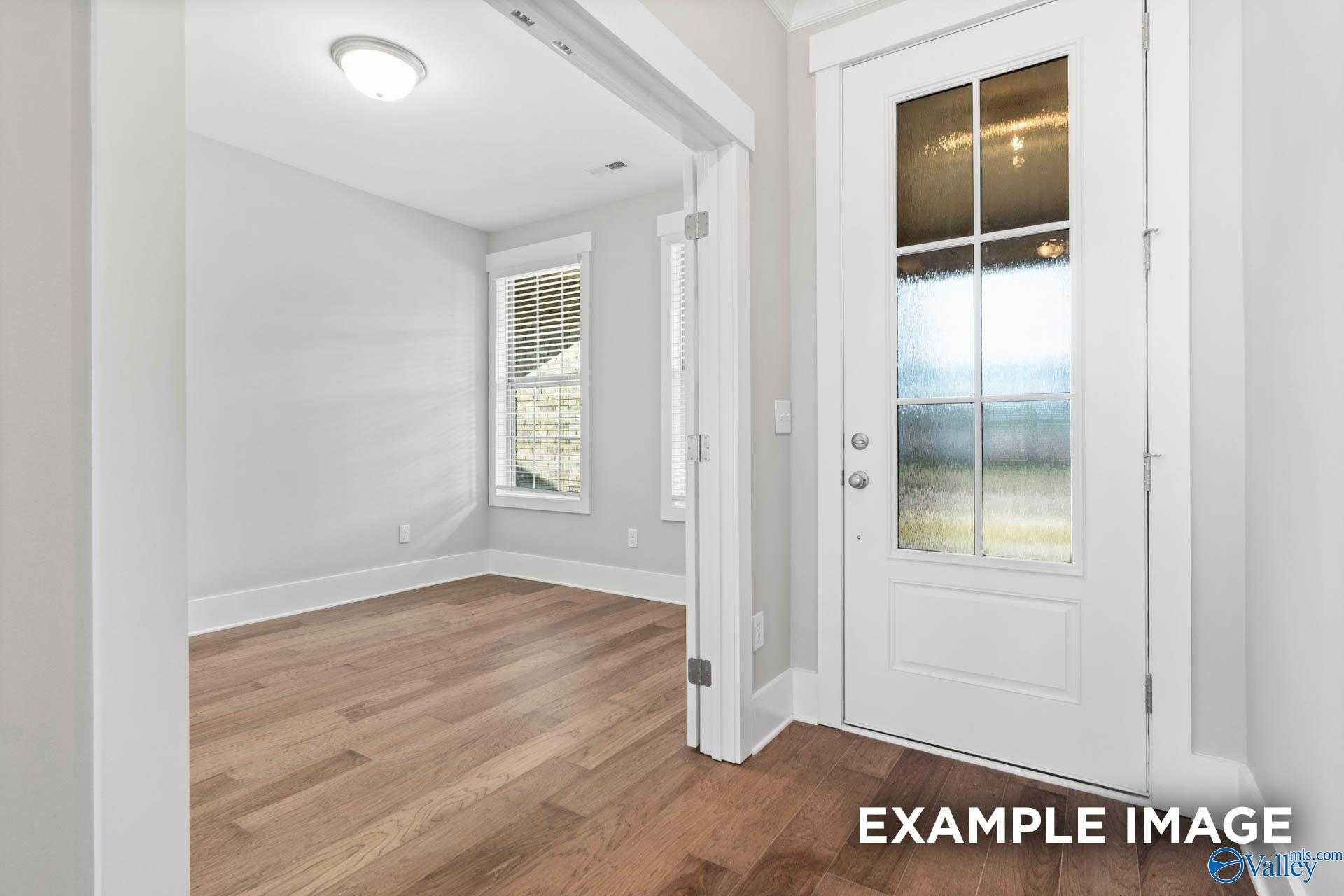 Bright interior room with hardwood floors, white walls, and glass-paneled back door in The Rockford 3-bedroom home, Meridianville, Alabama