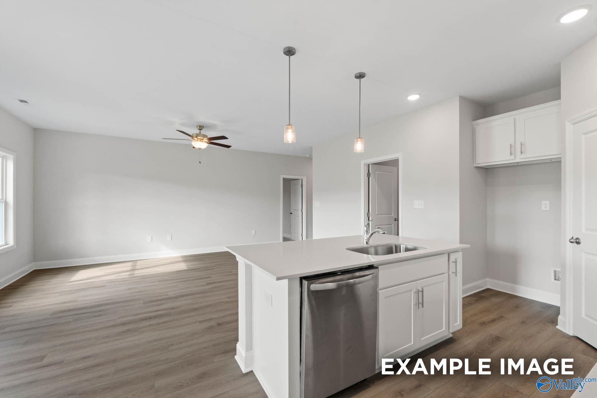 Modern open-concept kitchen with white island, stainless dishwasher, pendant lights, and ceiling fan in Davidson Homes The Butler, Huntsville, AL