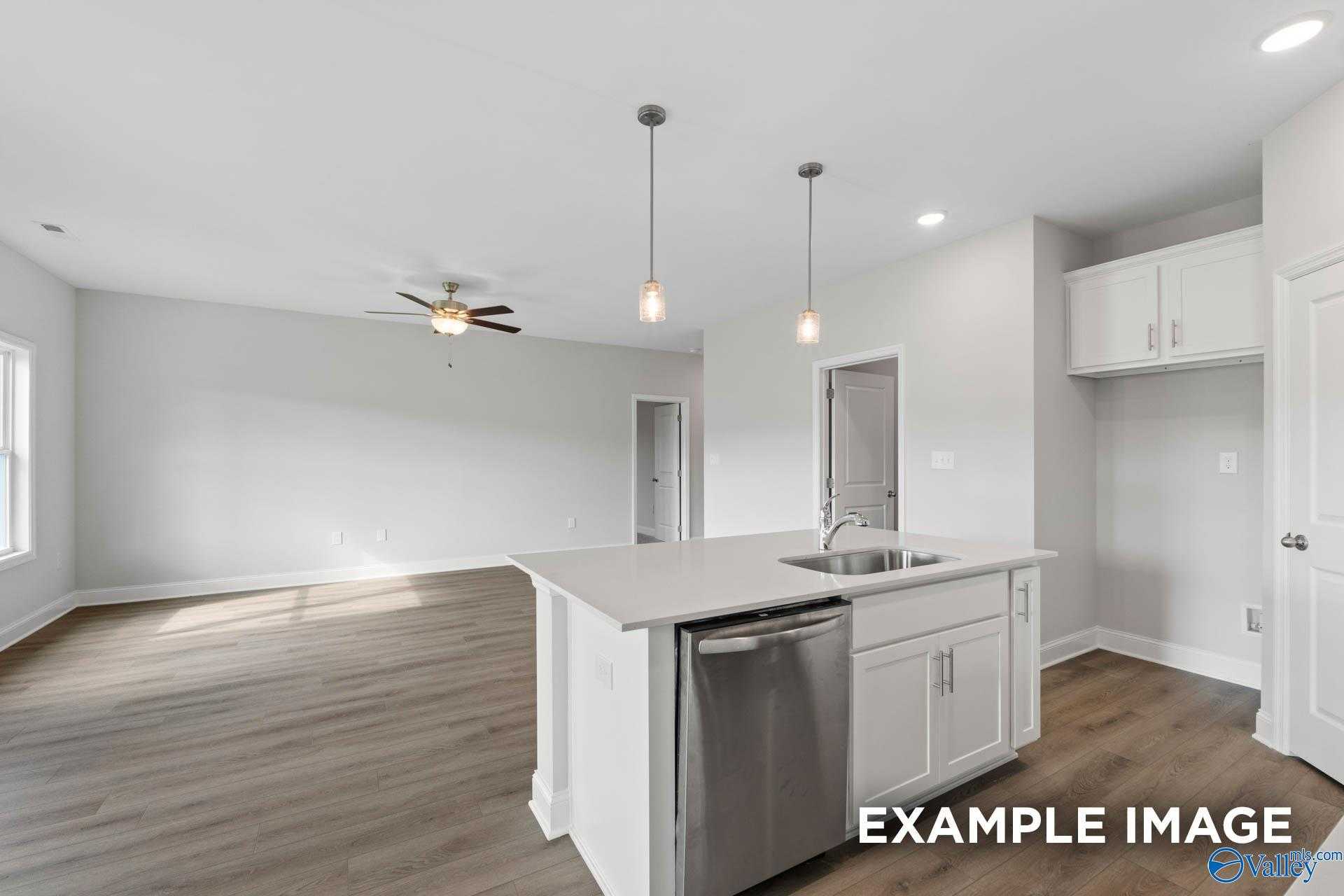 Modern open-concept kitchen with white island, stainless dishwasher, pendant lights, and ceiling fan in Davidson Homes The Butler, Huntsville, AL
