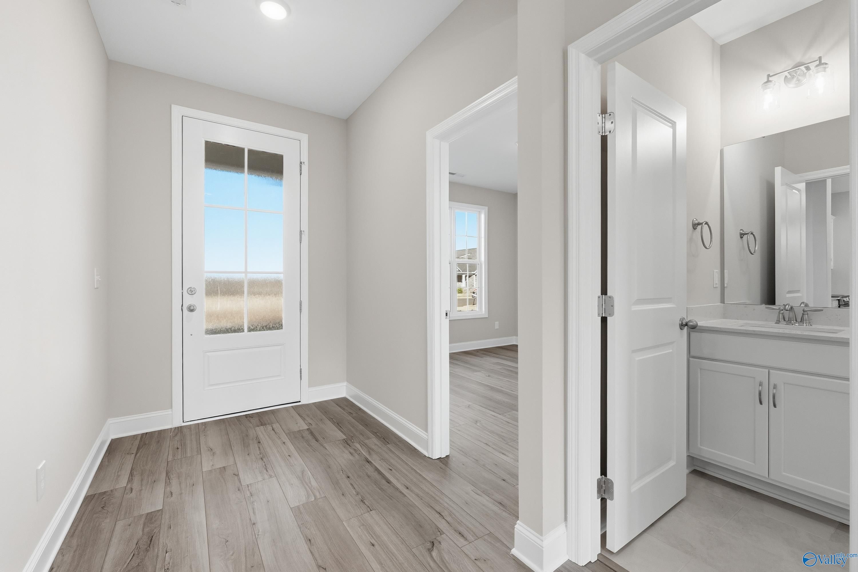 Bright mudroom with French door to backyard view and adjacent powder room with white vanity in Davidson Homes The Lanier, Toney, Alabama