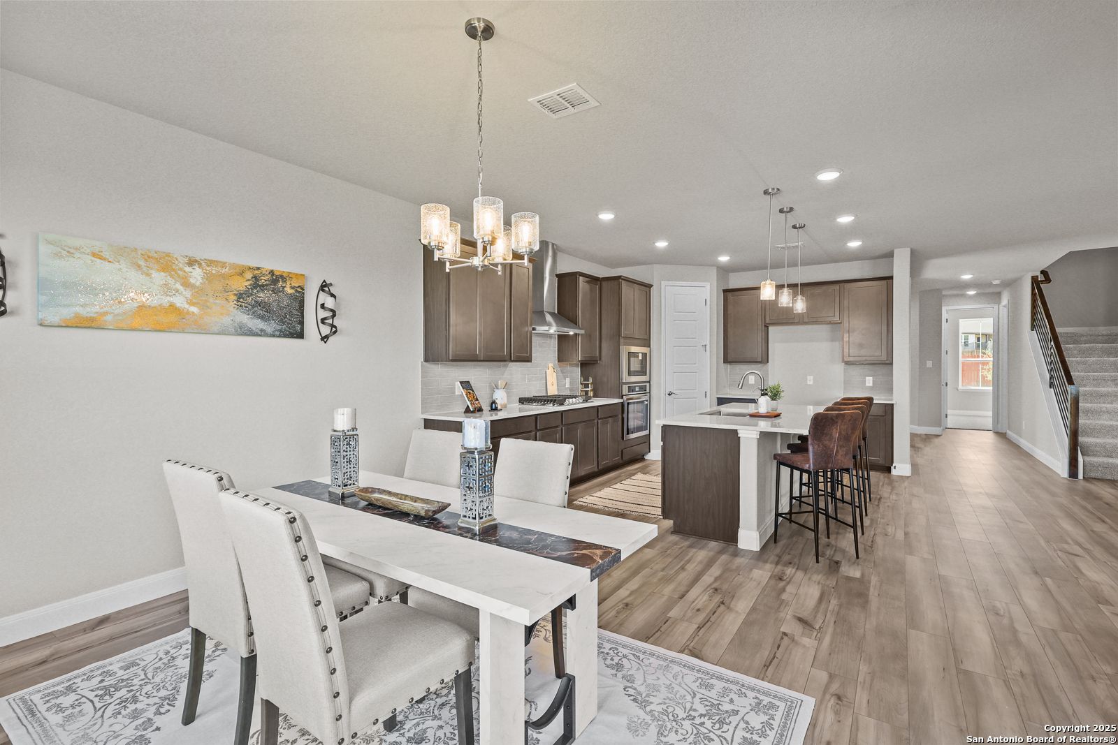 Open-concept kitchen with island, bar stools, and dining table in Davidson Homes The Jennings G, Castroville, Texas