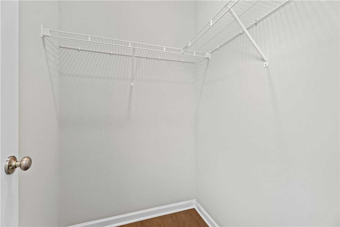 Spacious walk-in closet with white wire shelving, gray walls, and hardwood floors in Evermore Homes The Orion, Cusseta, Alabama