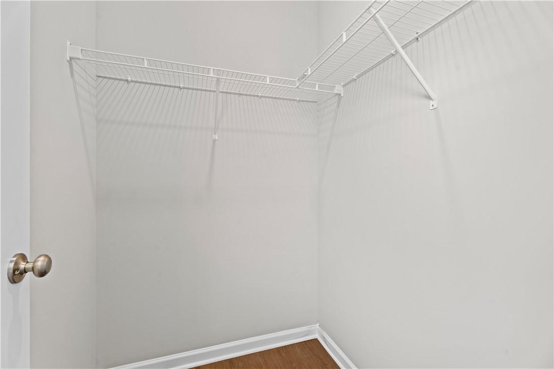 Spacious corner walk-in closet with white wire shelving and hardwood floors in Evermore Homes The Orion, Cusseta Alabama