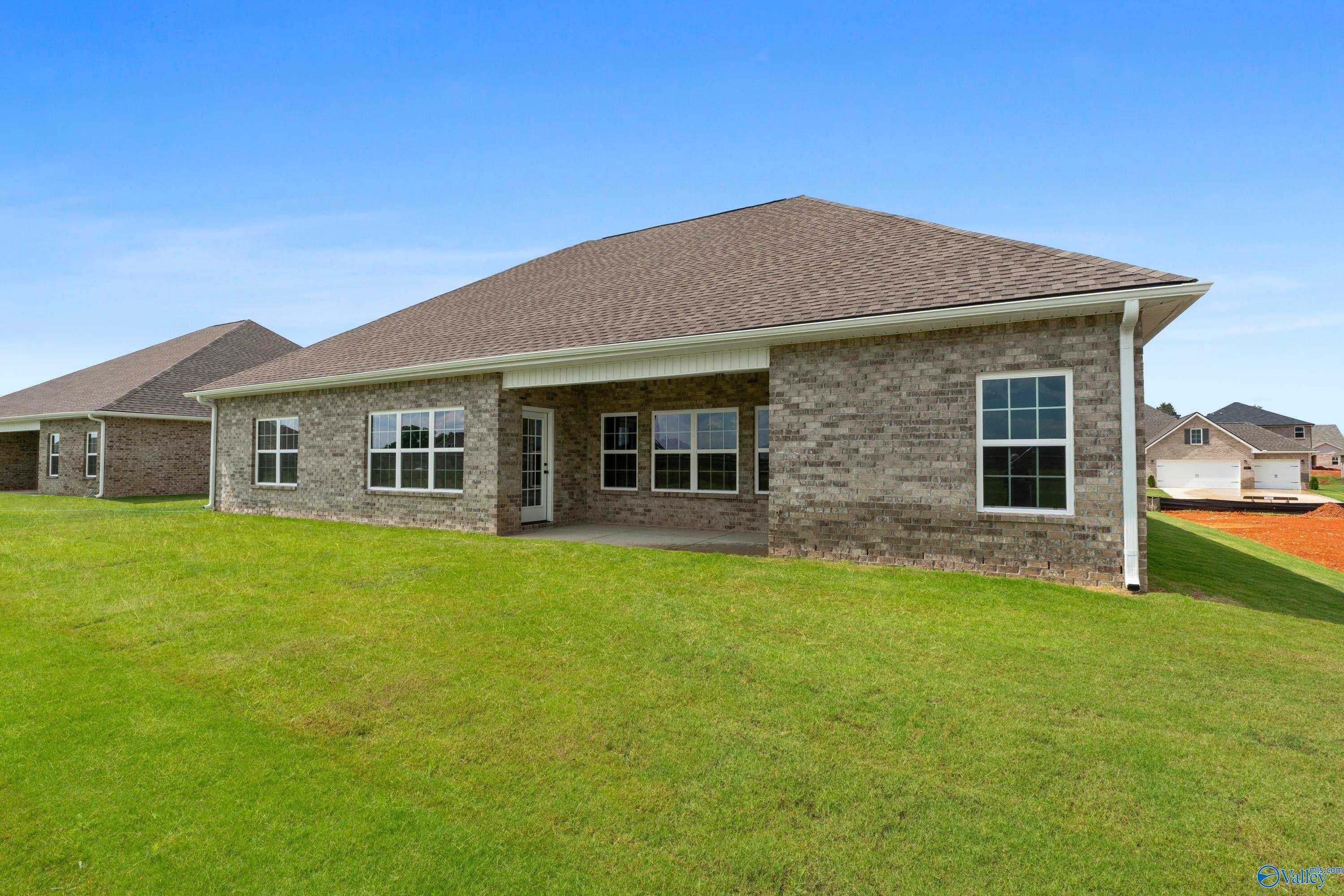 Single-story brick home exterior with covered porch, large windows, and green lawn in Kendall Farms, Toney, Alabama - Davidson Homes Finleigh