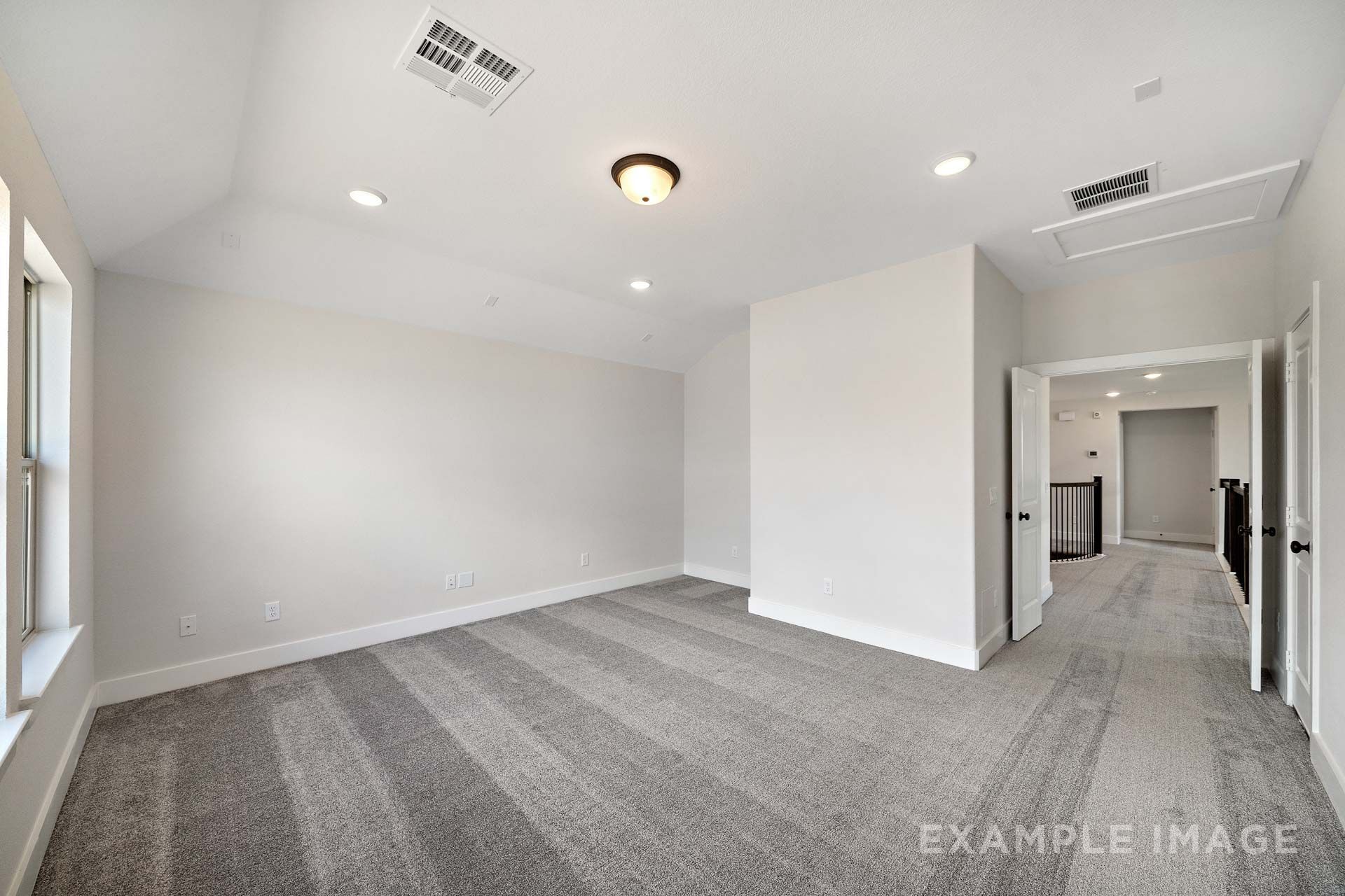 Spacious bedroom in The Victoria by Davidson Homes with vaulted ceiling, gray carpet, and natural light, Texas City, TX