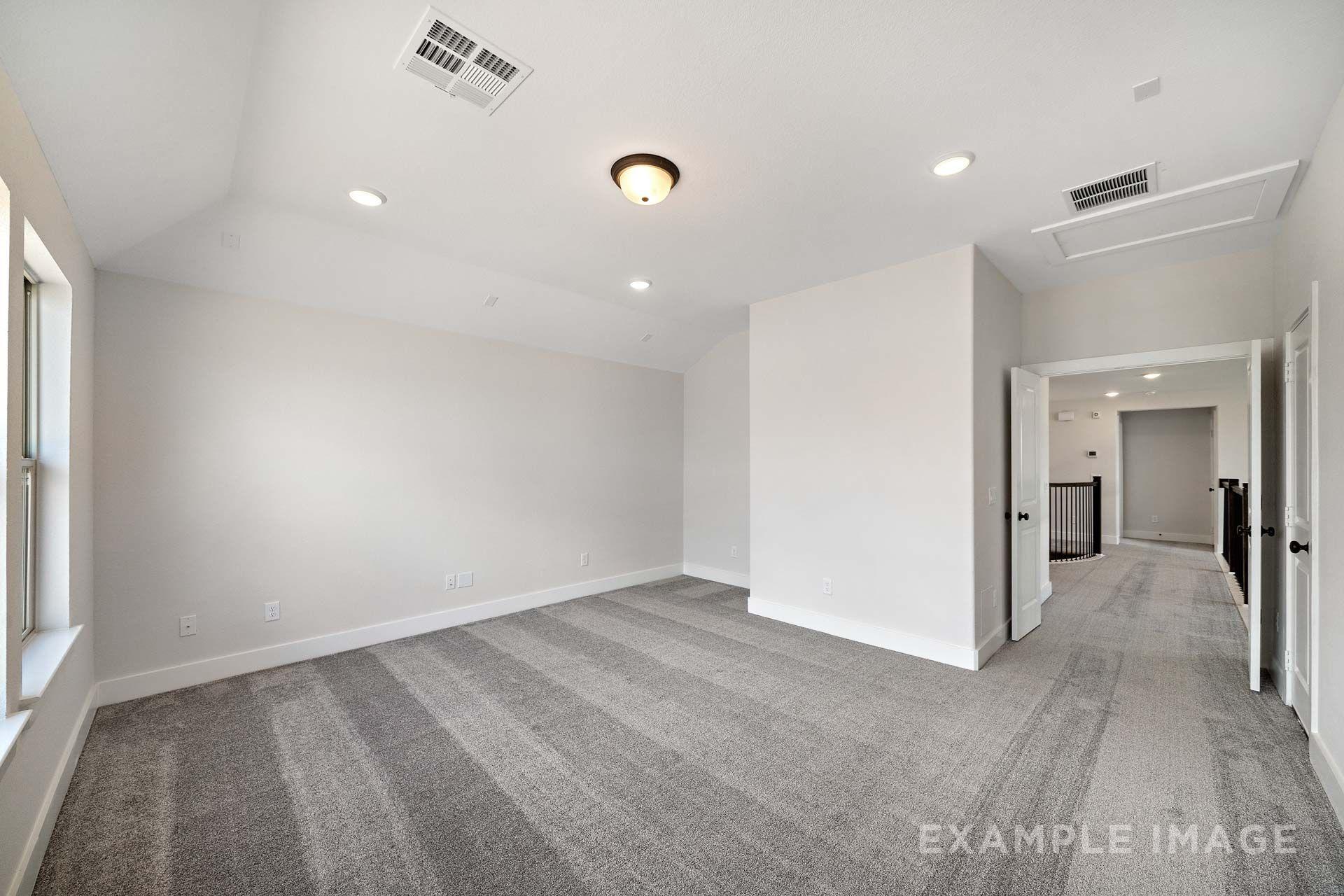 Spacious bedroom in The Victoria by Davidson Homes with vaulted ceiling, gray carpet, and natural light, Texas City, TX