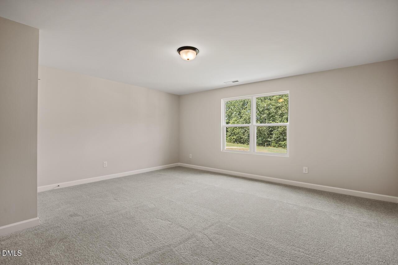 Spacious bedroom with plush carpet and natural light in The Ash C floor plan at Woodland Crossing, Zebulon, North Carolina.