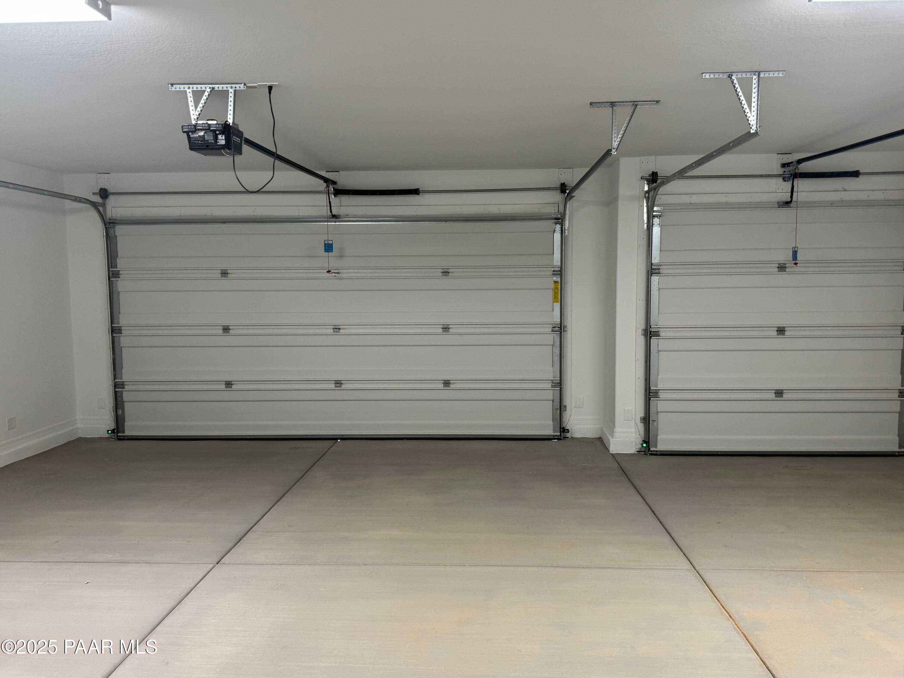 Spacious 3-car garage with white overhead doors and concrete flooring in The Monarch E by Davidson Homes, Prescott, Arizona