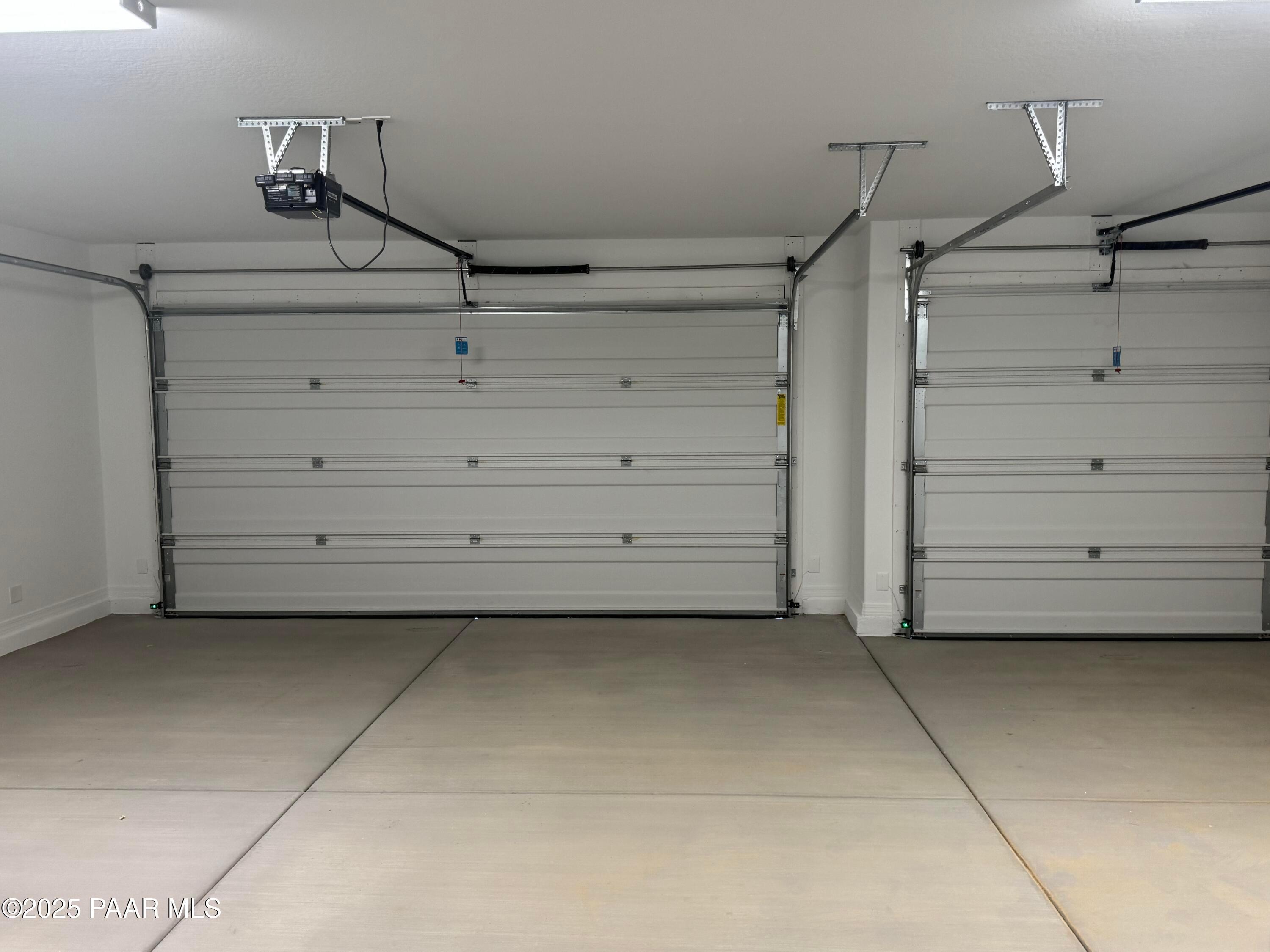 Spacious 3-car garage with white overhead doors and concrete flooring in The Monarch E by Davidson Homes, Prescott, Arizona