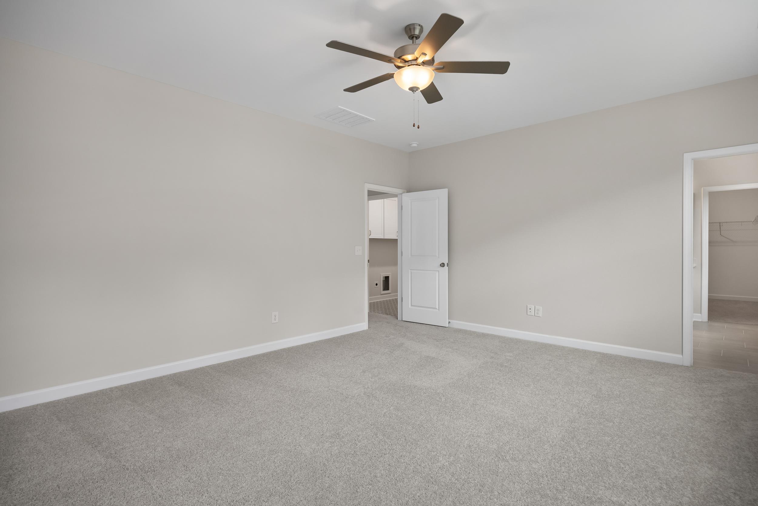 Spacious master bedroom in The Beech A with gray walls, ceiling fan, en-suite bath door, and walk-in closet access