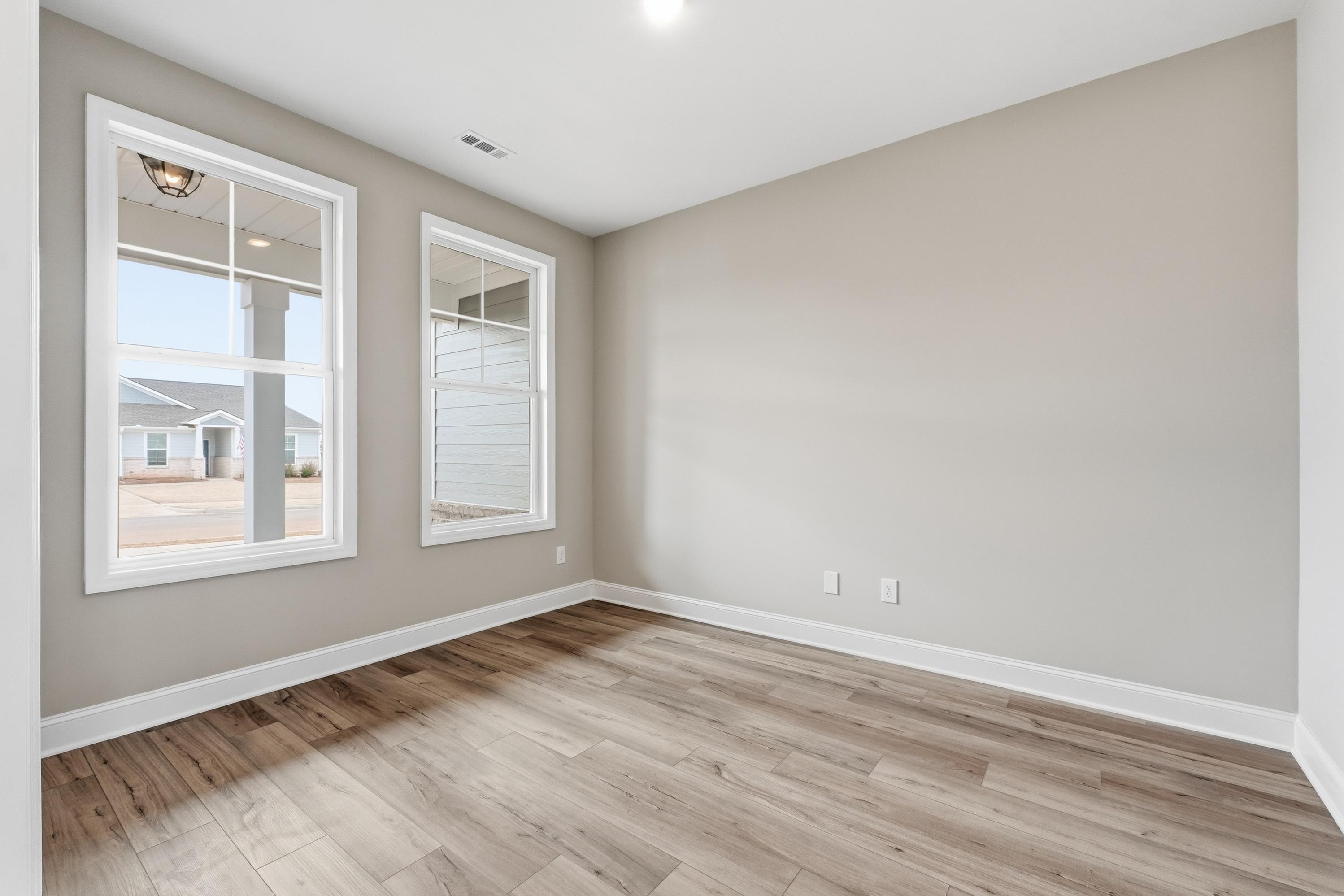Spacious secondary bedroom in The Rockford plan with beige walls, large double windows, and luxury vinyl plank flooring