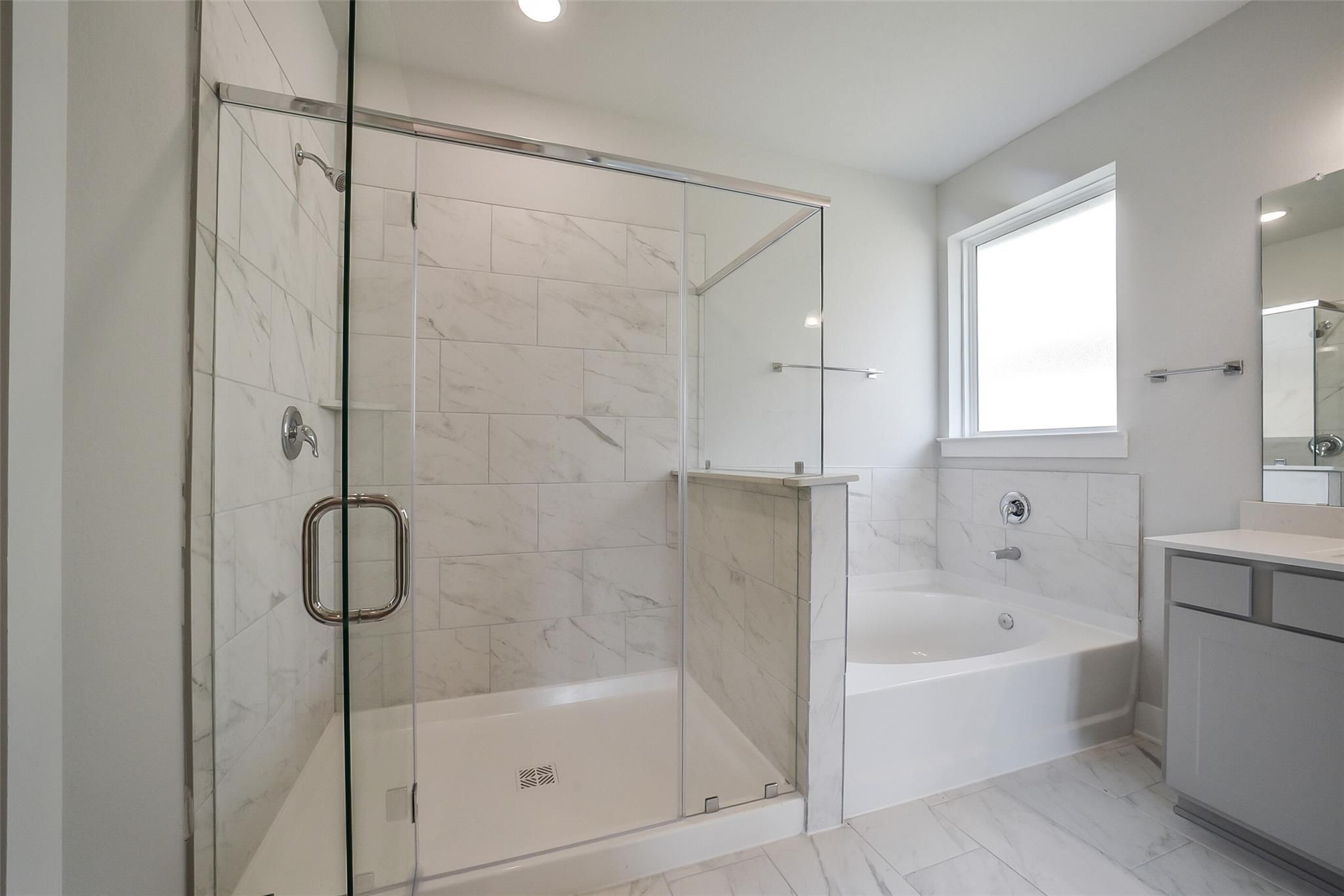 Elegant master bathroom with frameless glass shower, soaking tub, subway tile, and double vanity in Davidson Homes The Philip B, Rosharon, Texas