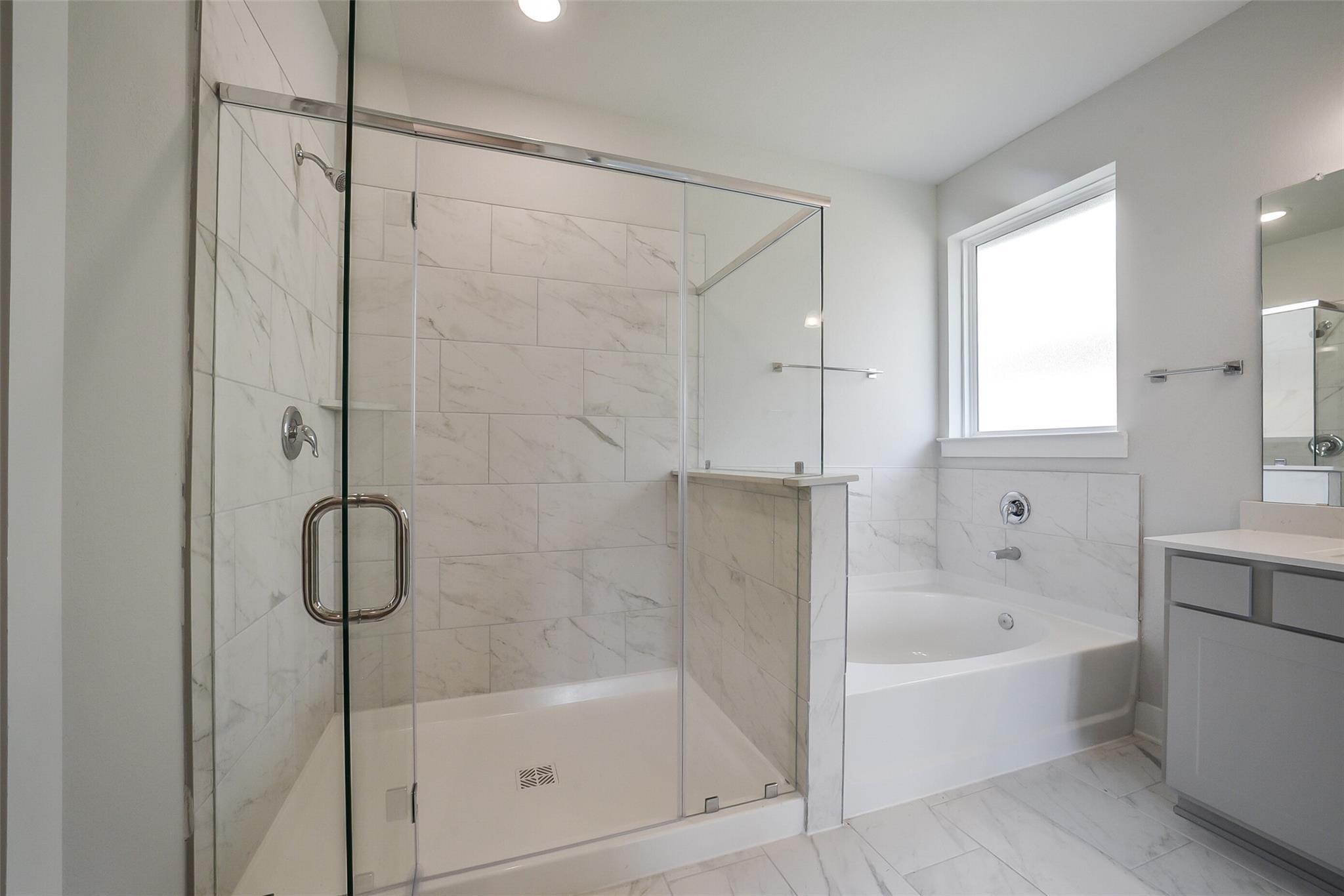 Elegant master bathroom with frameless glass shower, soaking tub, subway tile, and double vanity in Davidson Homes The Philip B, Rosharon, Texas