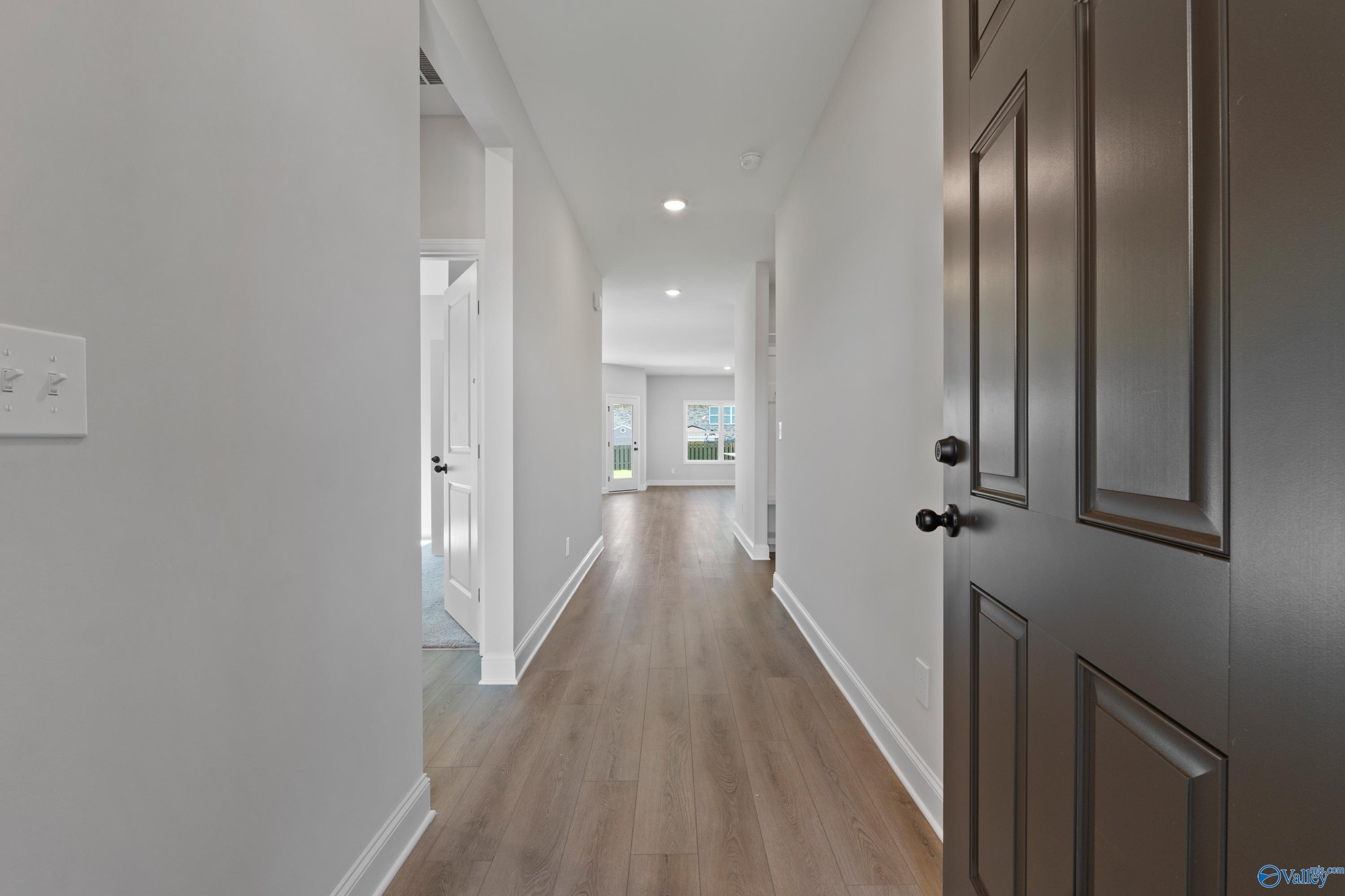 Bright hallway with light hardwood floors, white walls, and natural light in Davidson Homes The Franklin C, Hazel Green, Alabama