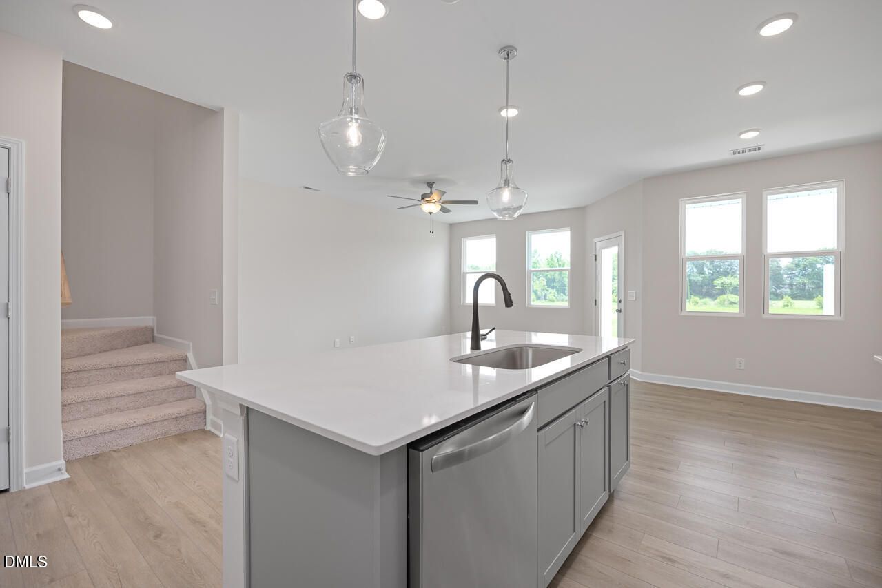 Modern kitchen island with quartz countertops and pendant lighting in The Graham floor plan, Springvale, Fuquay-Varina.