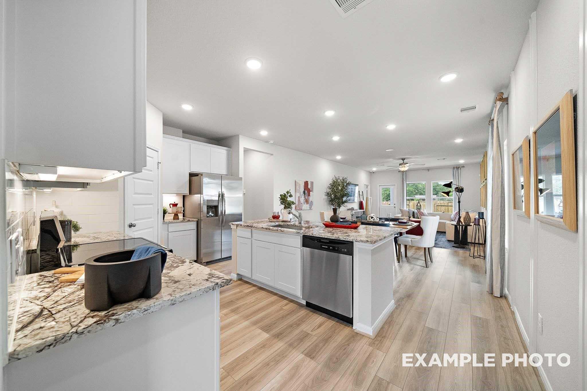 Modern open-concept kitchen with white cabinets, granite counters, stainless appliances in The San Marcos E, Conroe, TX