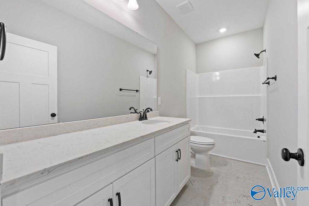 Modern bathroom with white subway tile shower, soaking tub, double vanity, and frameless mirror in Evermore Homes The Oxford, Owens Cross Roads, AL