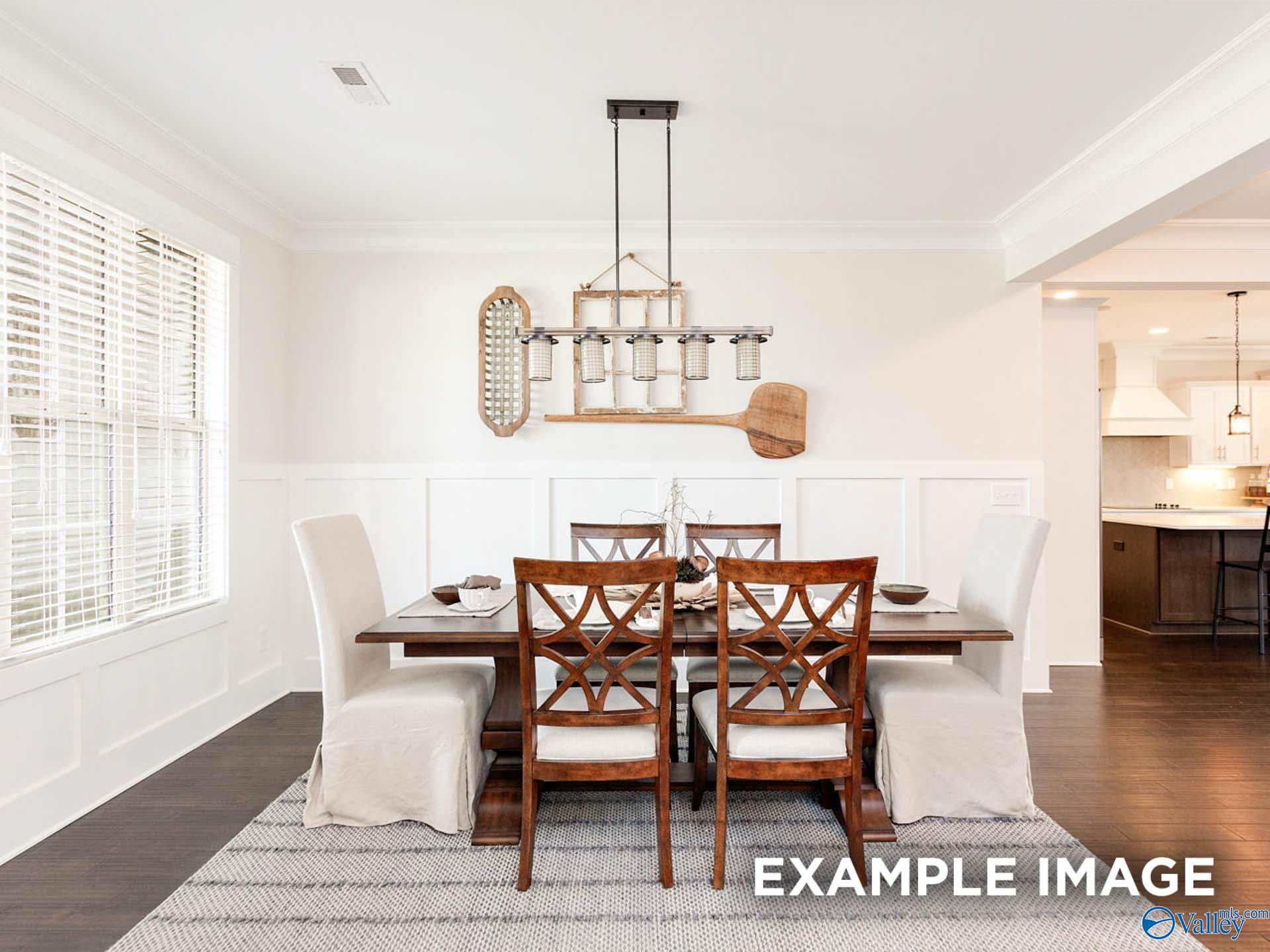 Elegant dining room featuring wooden table with upholstered chairs, rustic chandelier, and wainscoting in The Finleigh home, Meridianville, AL