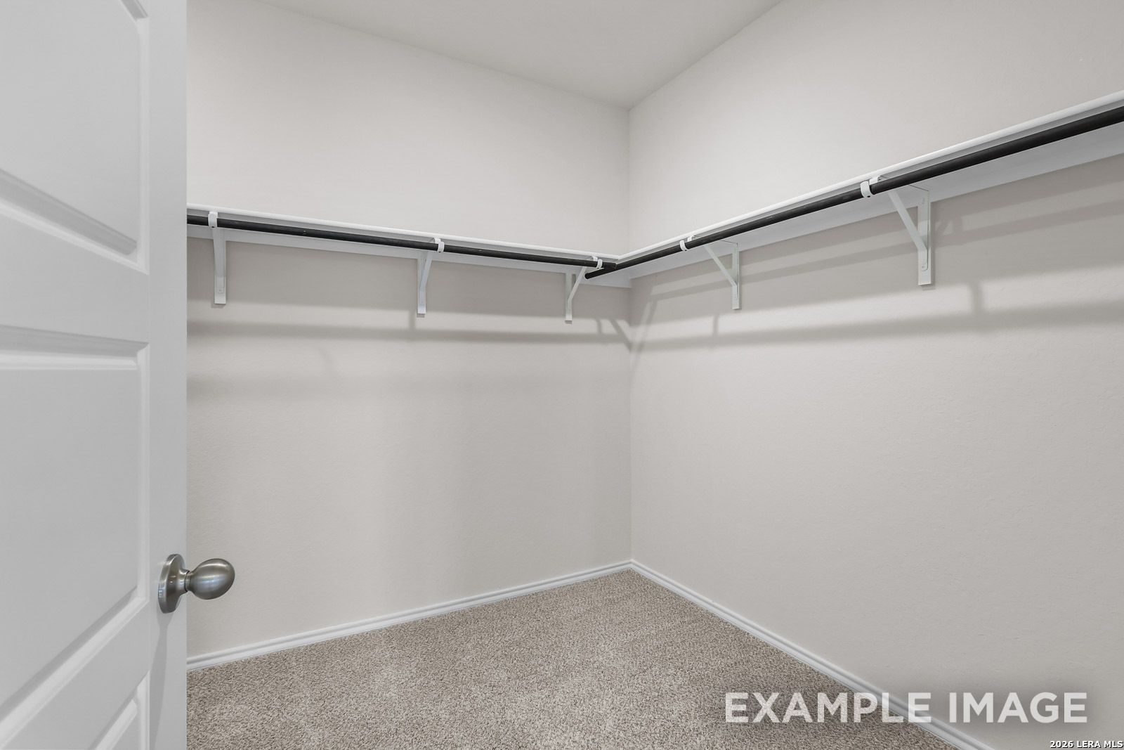 Walk-in closet with neutral carpeting and built-in shelving in The Sequoia C floor plan by Davidson Homes in San Antonio.