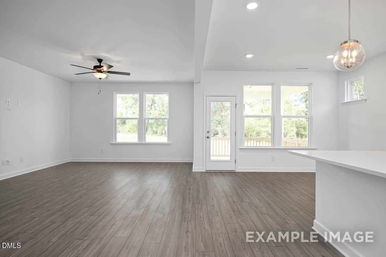 Spacious open-concept great room with hardwood floors, white kitchen island, French doors, and large windows in Davidson Homes The Willow D, Zebulon, NC