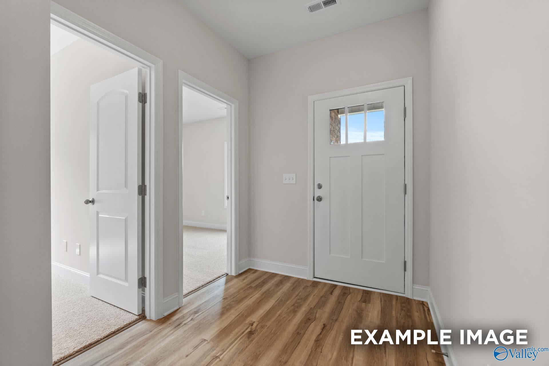 Bright entry foyer with light gray walls, oak hardwood floors, and white doors in Davidson Homes The Butler, Toney, Alabama