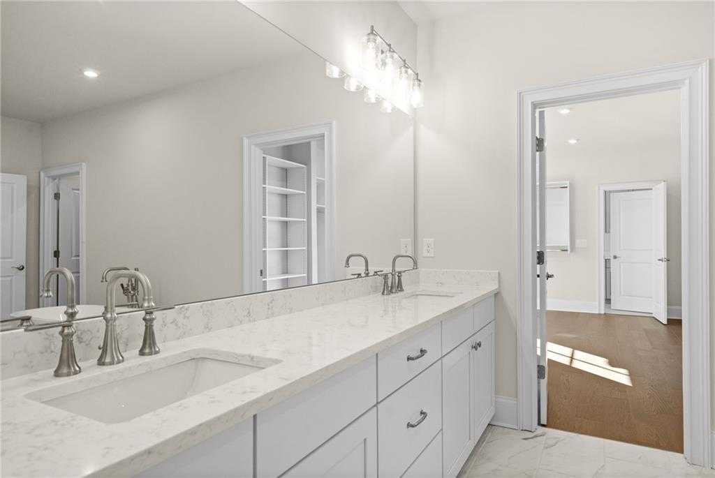 Elegant double vanity bathroom with white quartz counters, chrome faucets, and large mirror in Davidson Homes The Arlington A, East Cobb, Georgia
