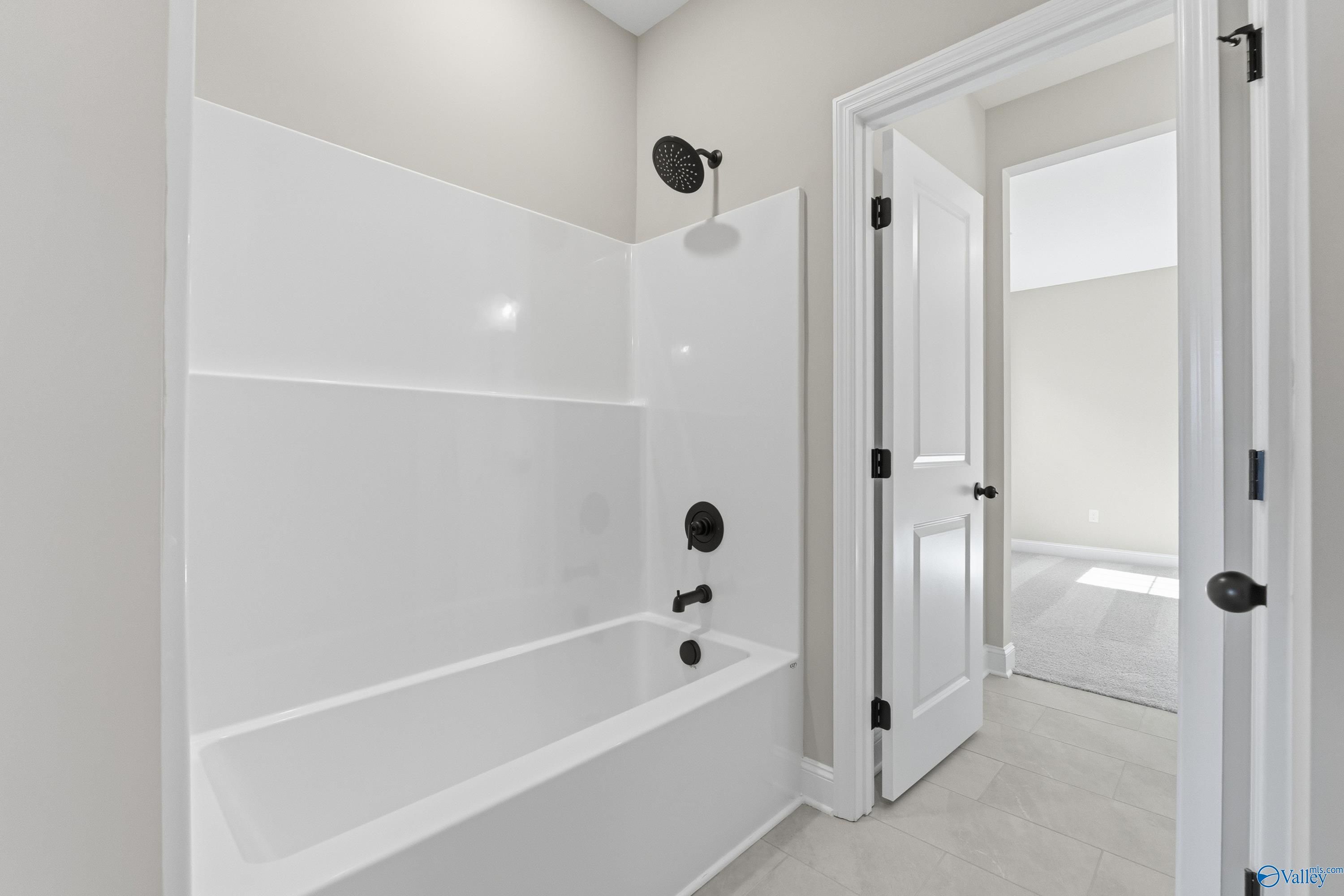 Modern bathroom featuring white tub, glass shower enclosure, and rainfall showerhead in Davidson Homes The Finleigh, Meridianville, Alabama